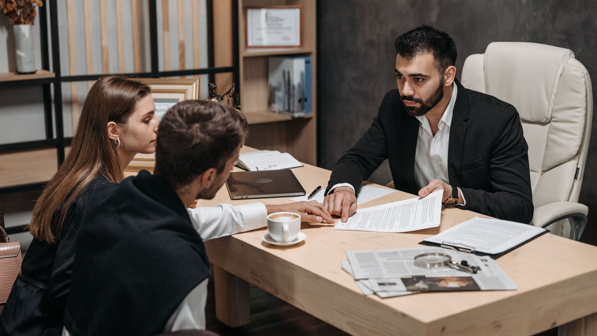 Lawyer discussing legal documents with clients at office desk.