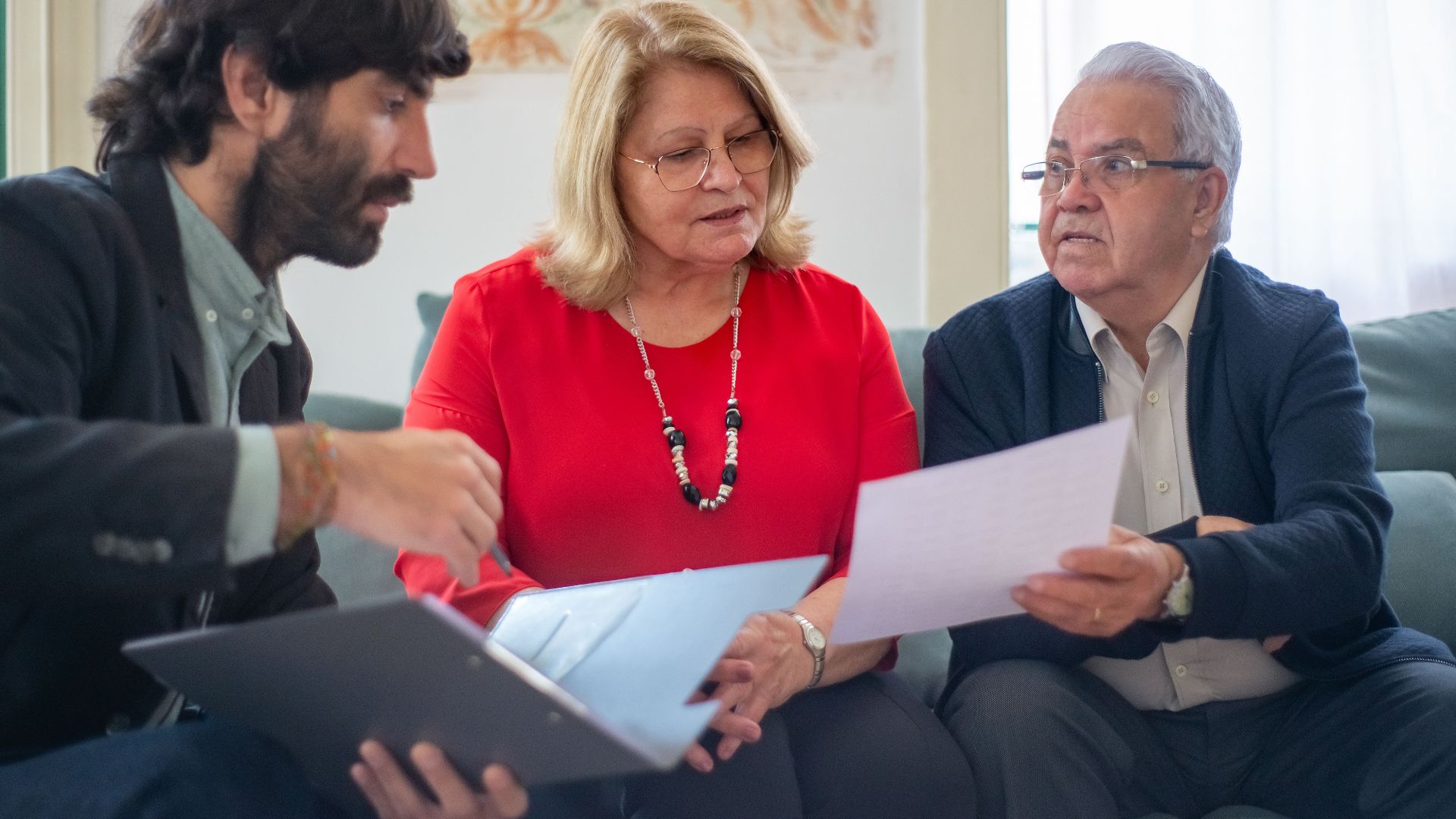 Senior couple consulting with a professional advisor, discussing documents indoors.