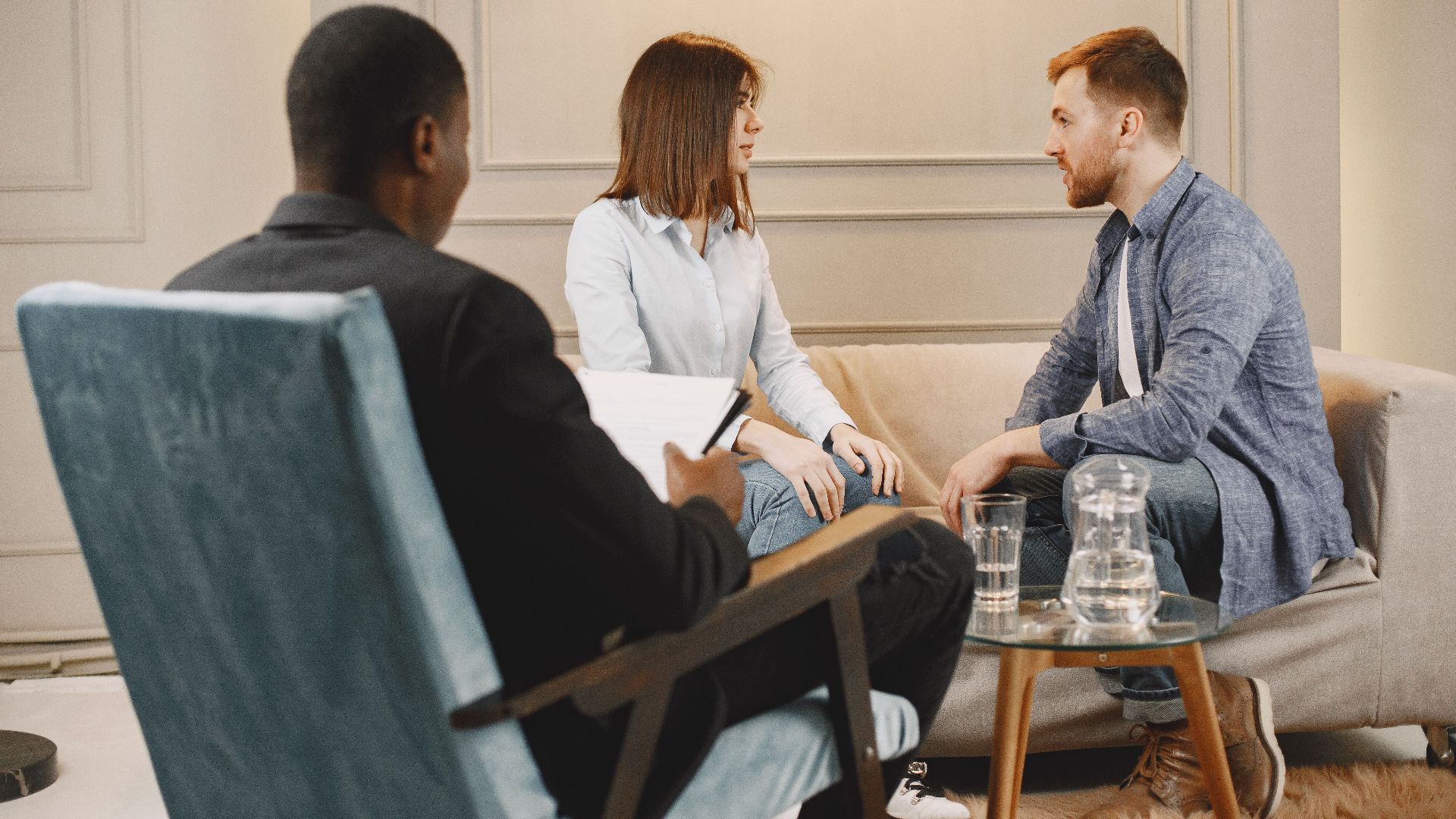 Couple in a counseling session with a therapist in a modern and cozy setting.