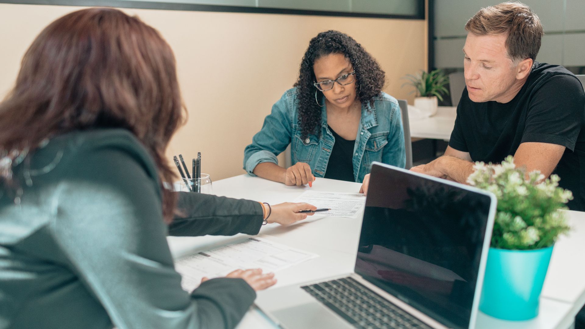 Couple meeting with advisor for adoption process in a modern office setting.