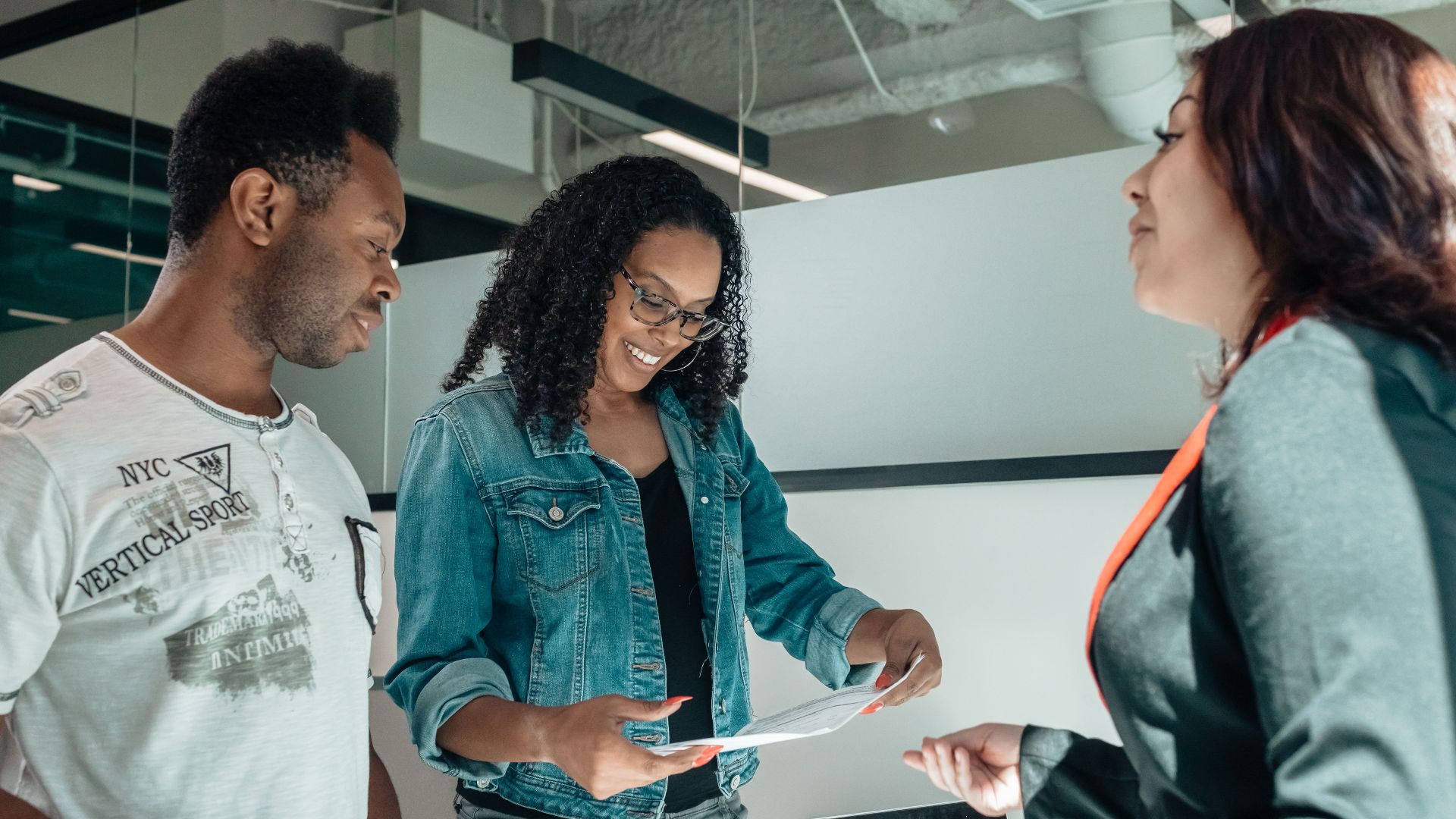Three adults engaging in a business discussion in a bright, modern office setting.