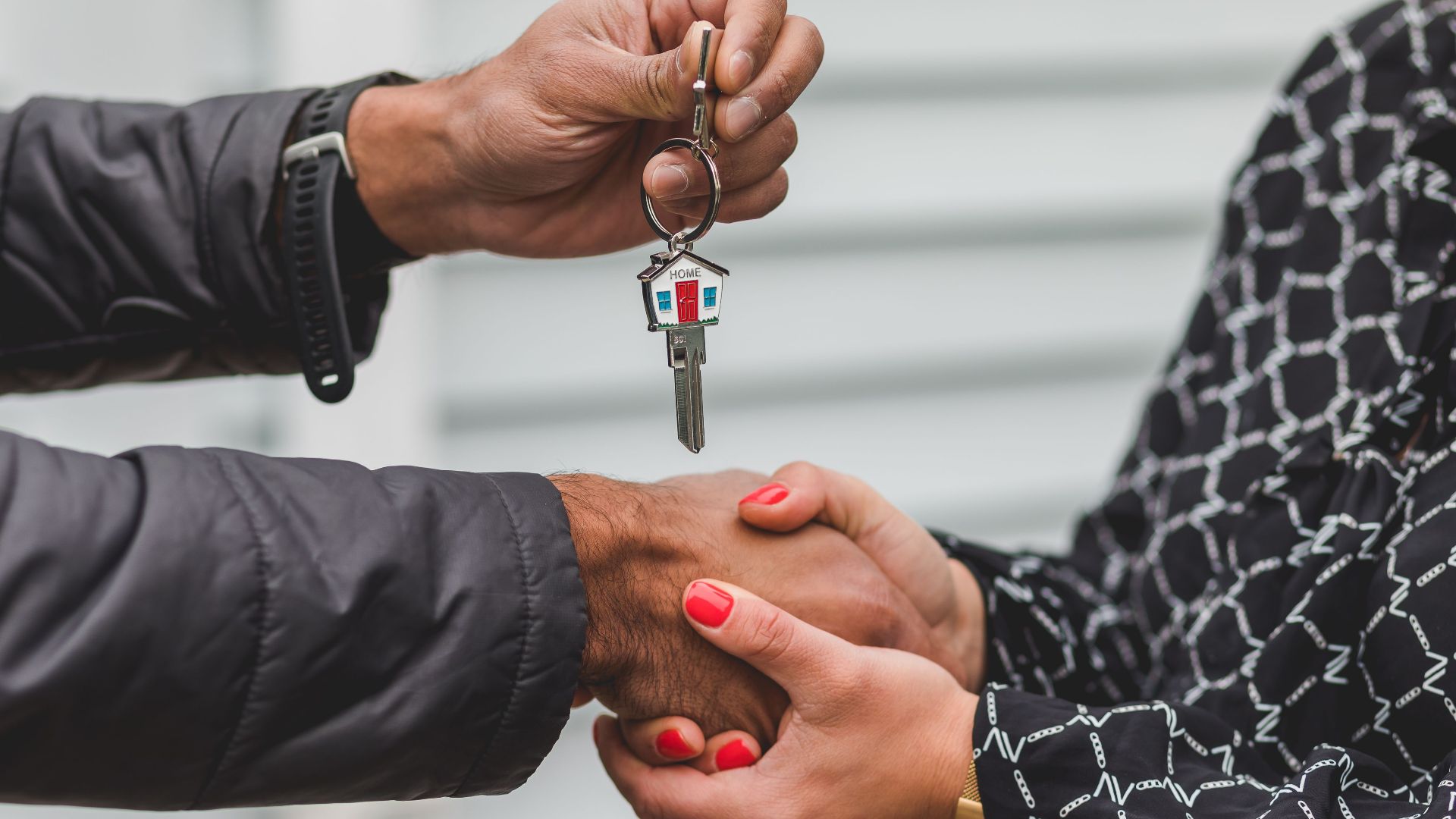 Close-up of a realtor handing over a house key to a new homeowner, symbolizing ownership and investment.