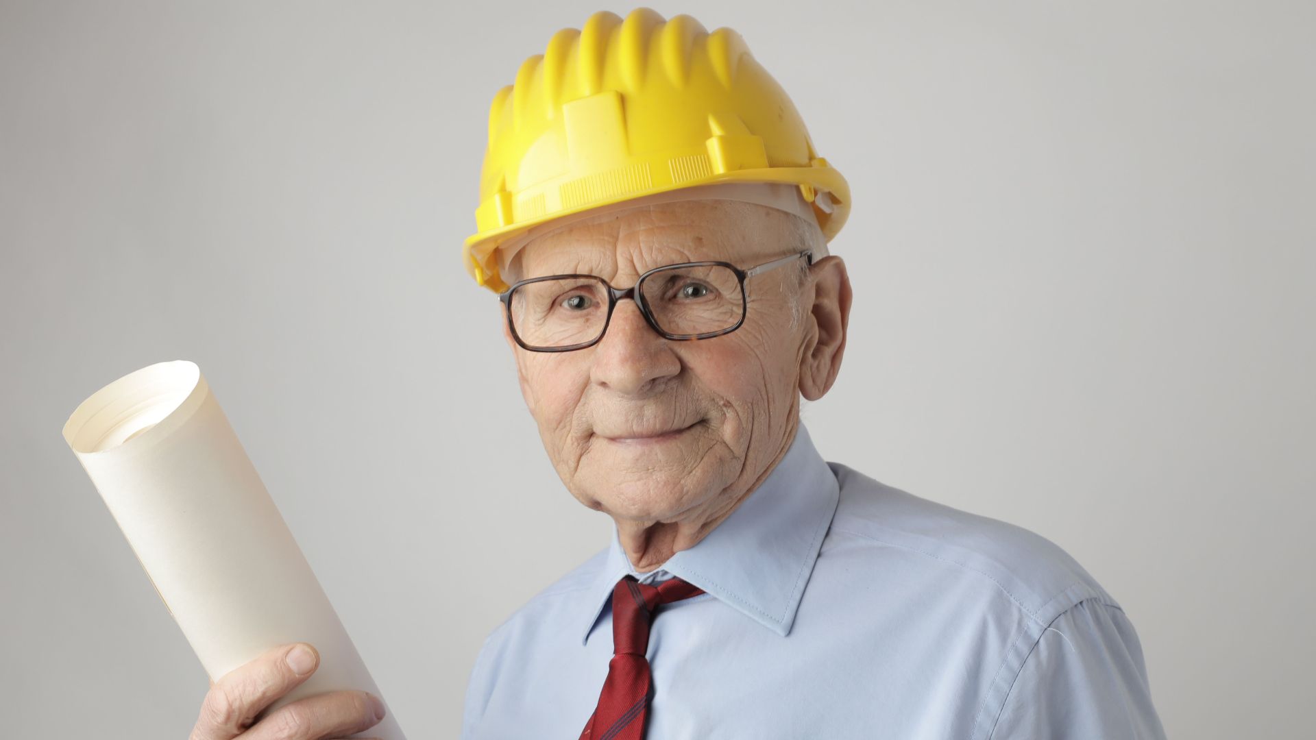 Senior engineer in safety gear holding blueprints, symbolizing experience and dedication in civil engineering.