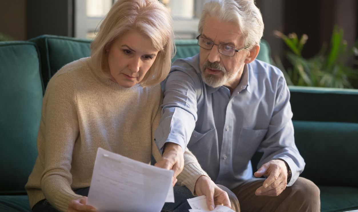 Serious grey haired mature couple calculating bills, checking finances together at home, senior retired old family reading documents, insurance paper, worried about loan, bankruptcy or money problem