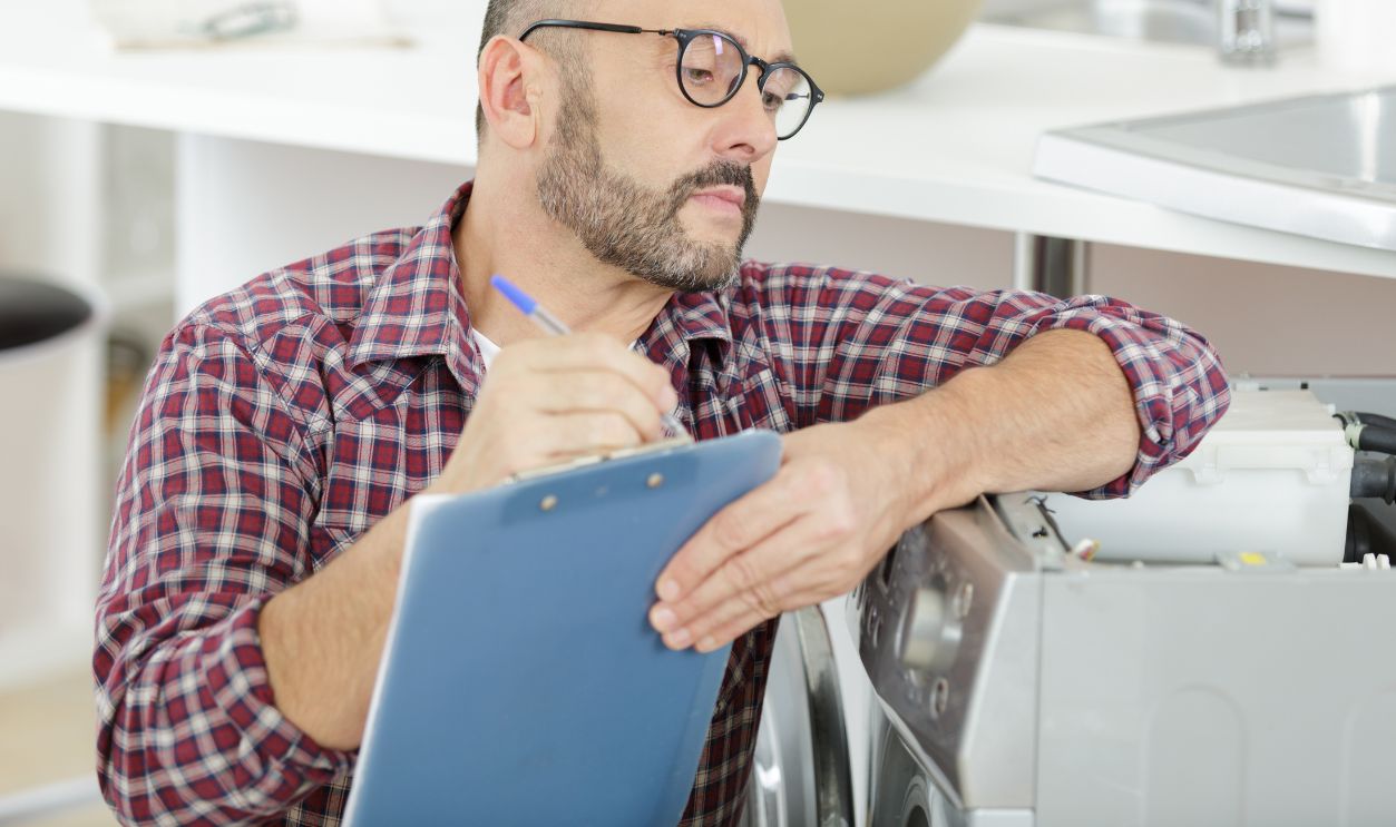 concentrated man is writing on a clipboard during DIY
