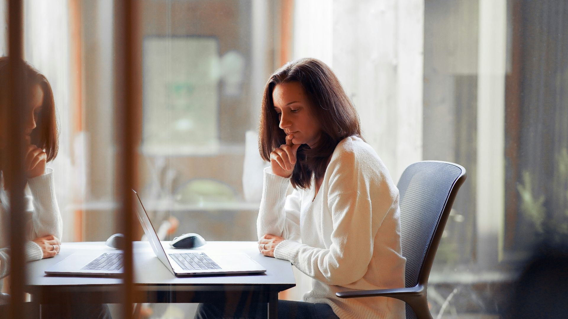 a woman sitting at a table with a laptop computer