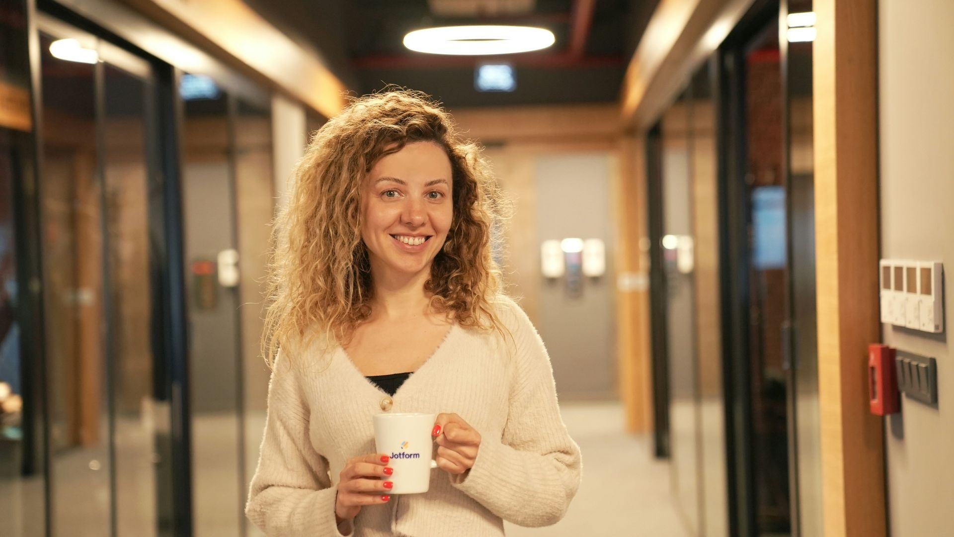 a woman holding a cup of coffee in a hallway