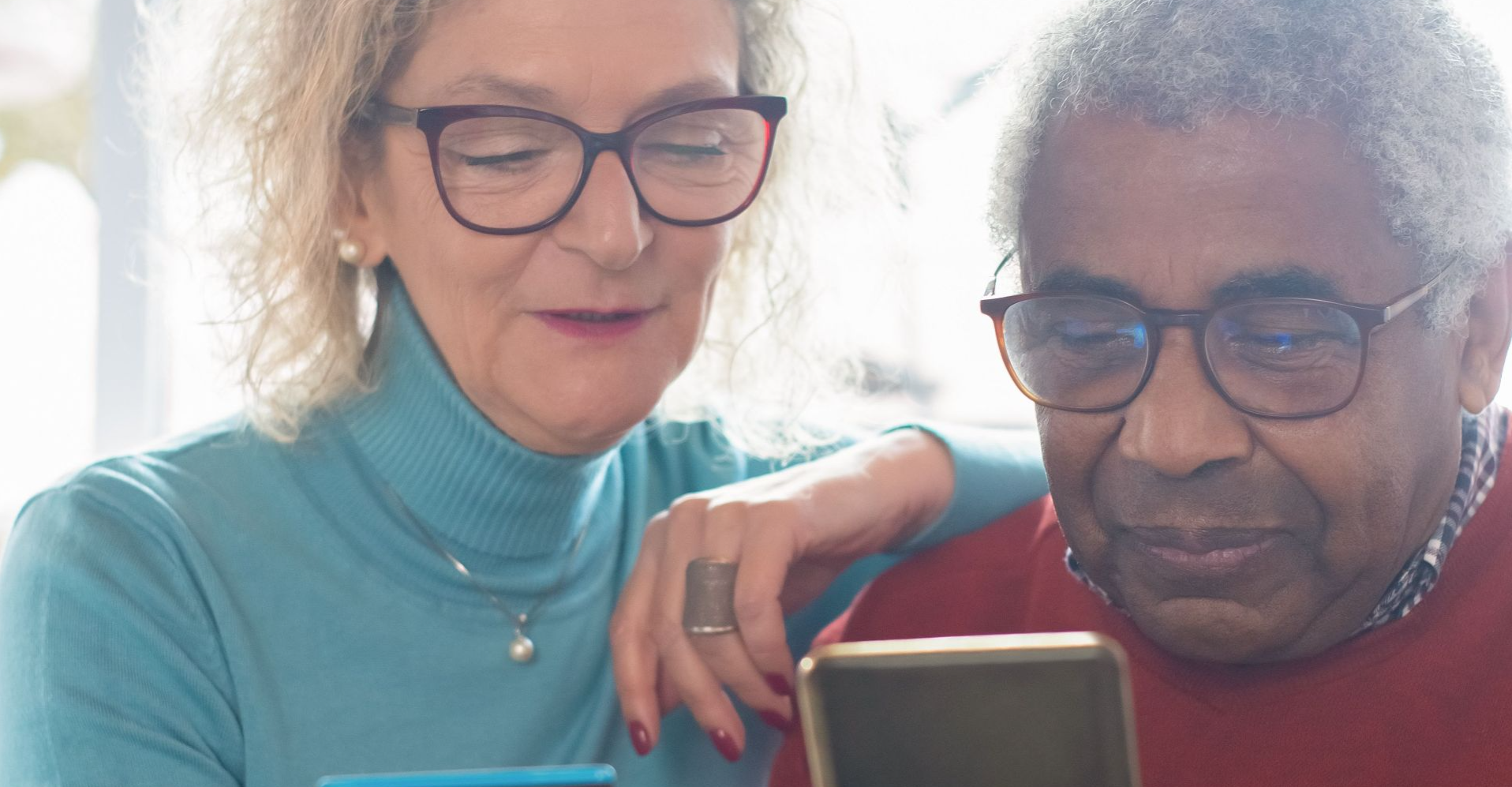 Elderly couple using smartphone and credit card for online shopping indoors.
