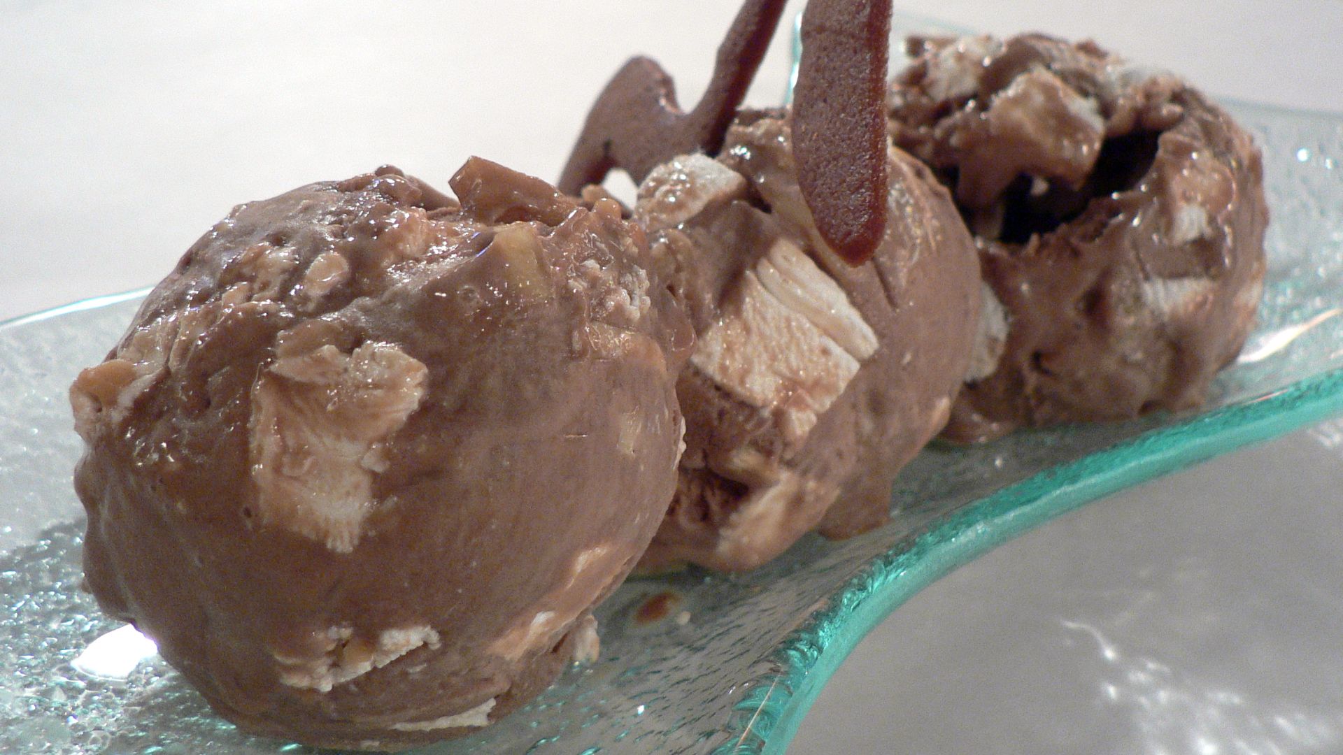 Three scoops of rocky road ice cream, with a chocolate cookie