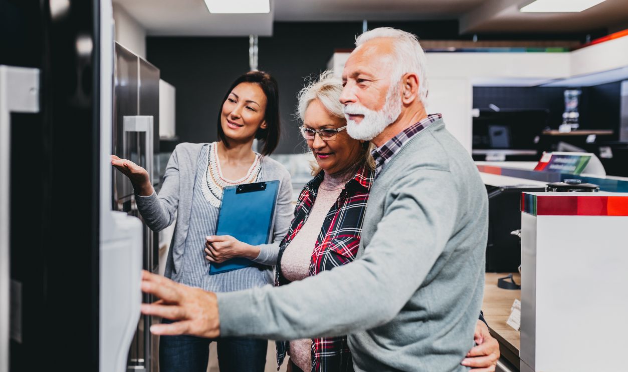 Senior husband and wife, satisfied customers choosing fridges in appliances store.