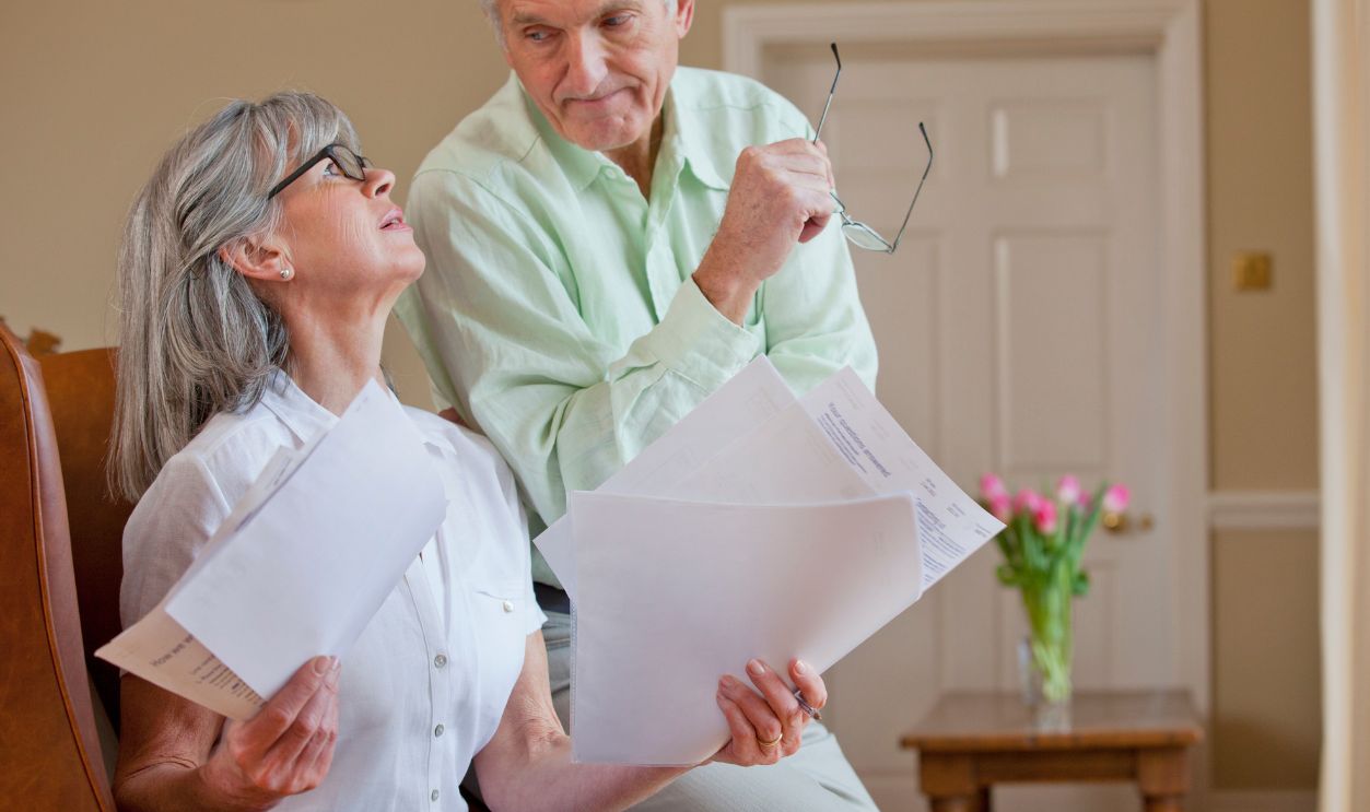 Horizontal shot of a senior couple discussing paperwork with the woman holding documents looks at her husband.