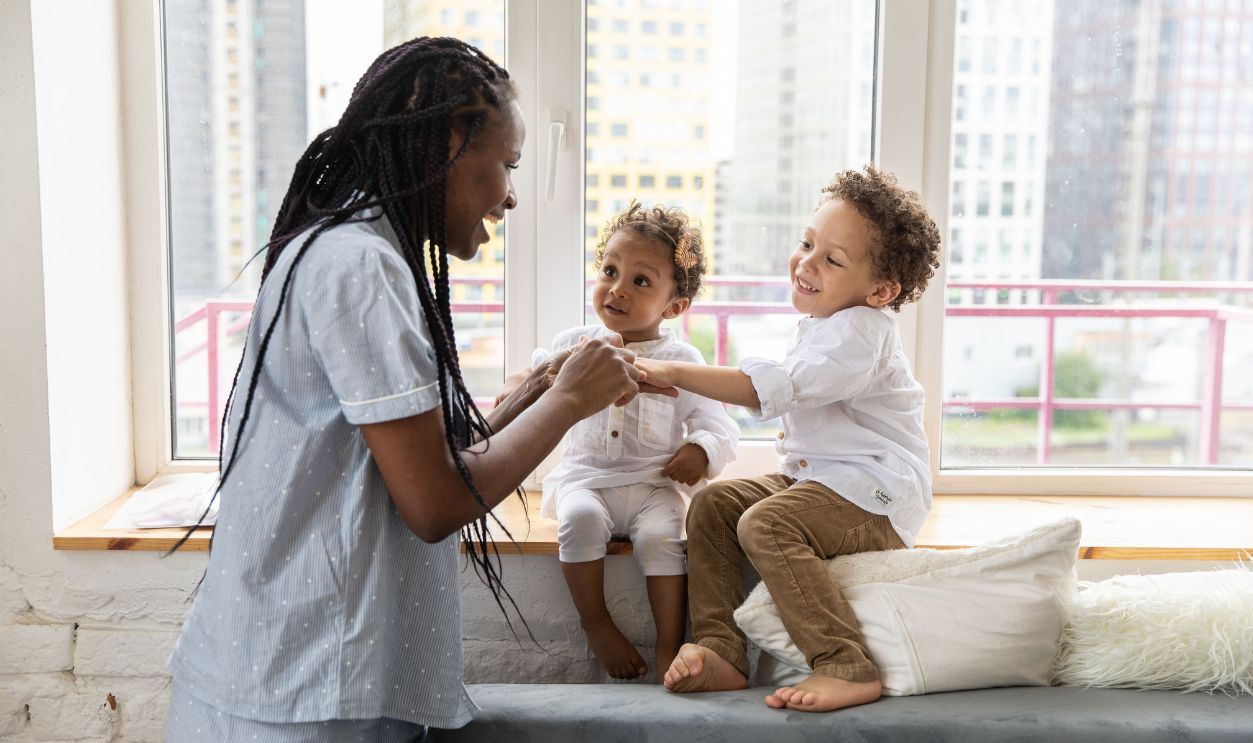 A mother and her two children share a joyful moment by a bright urban