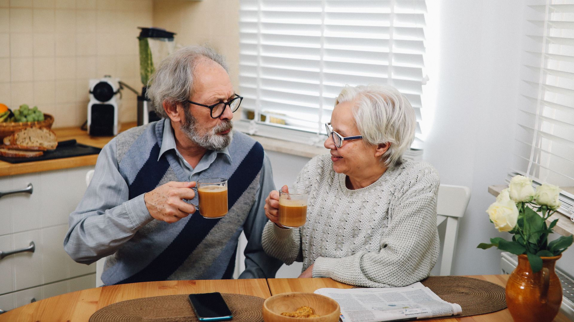 Senior couple enjoying coffee together at home in cozy kitchen setting.