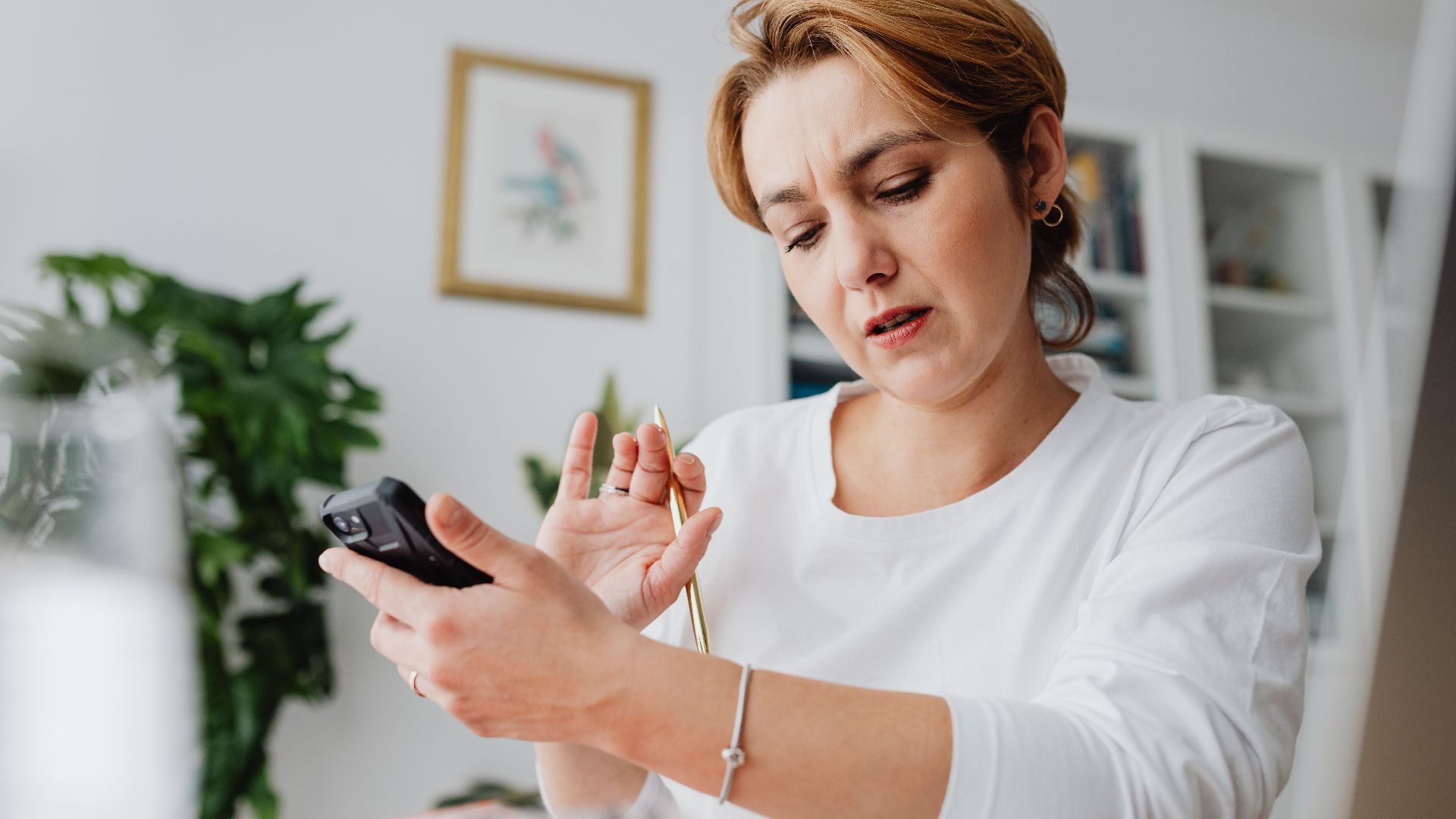 A woman intensely focuses on a calculator while managing work from a home office setup.