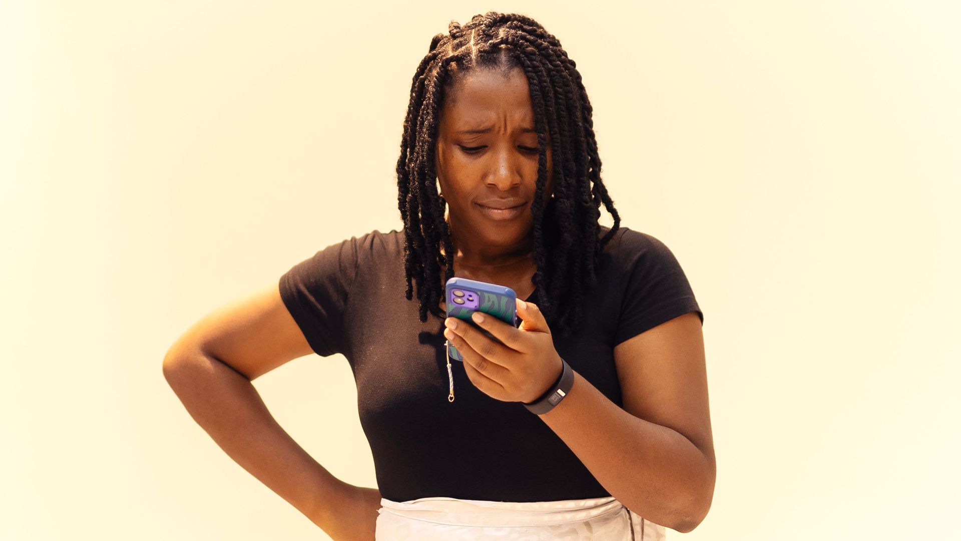 A young woman with braids looks at her phone in Lagos, Nigeria.