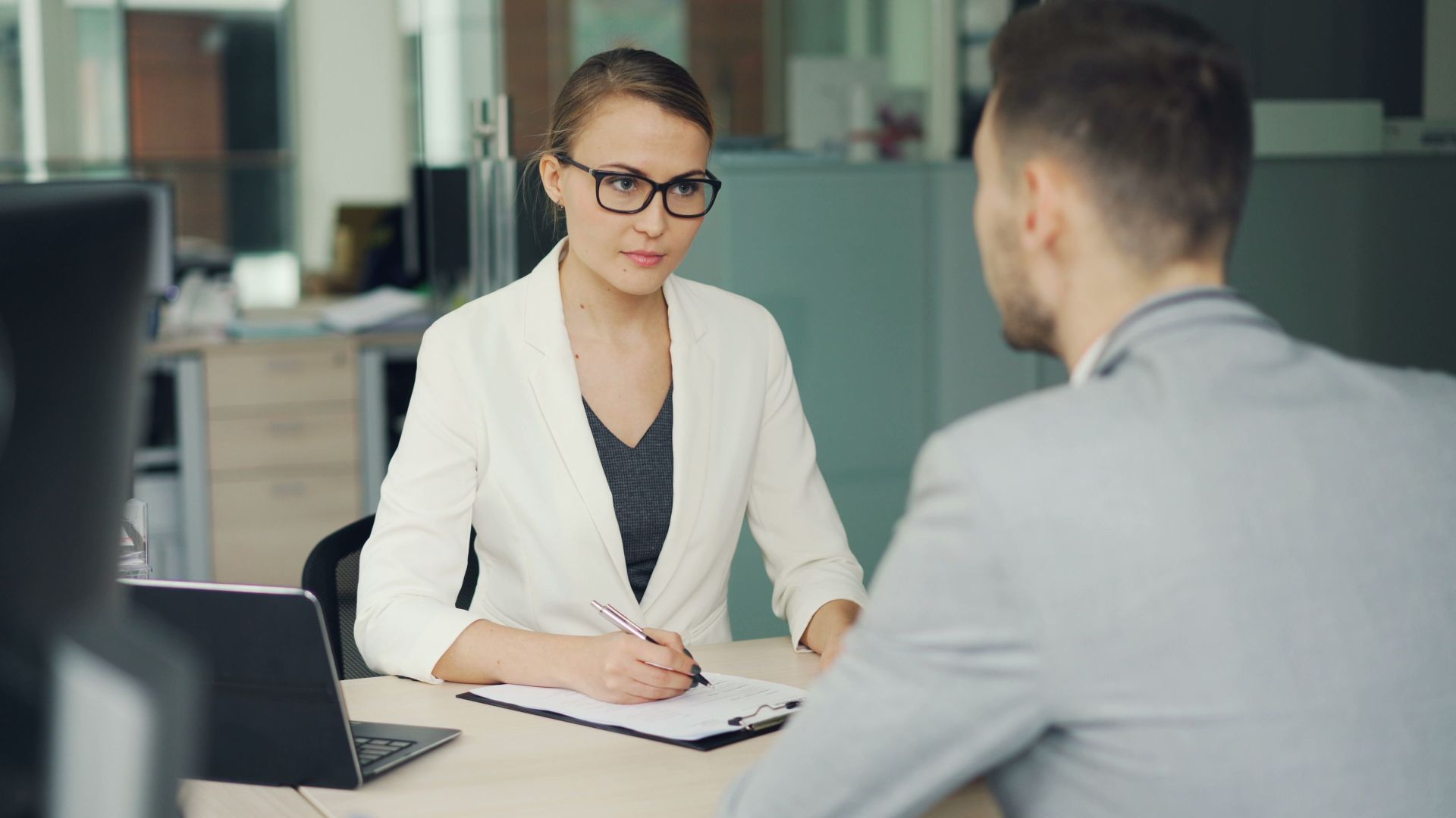 Two professionals in a serious business meeting at a modern office setting.