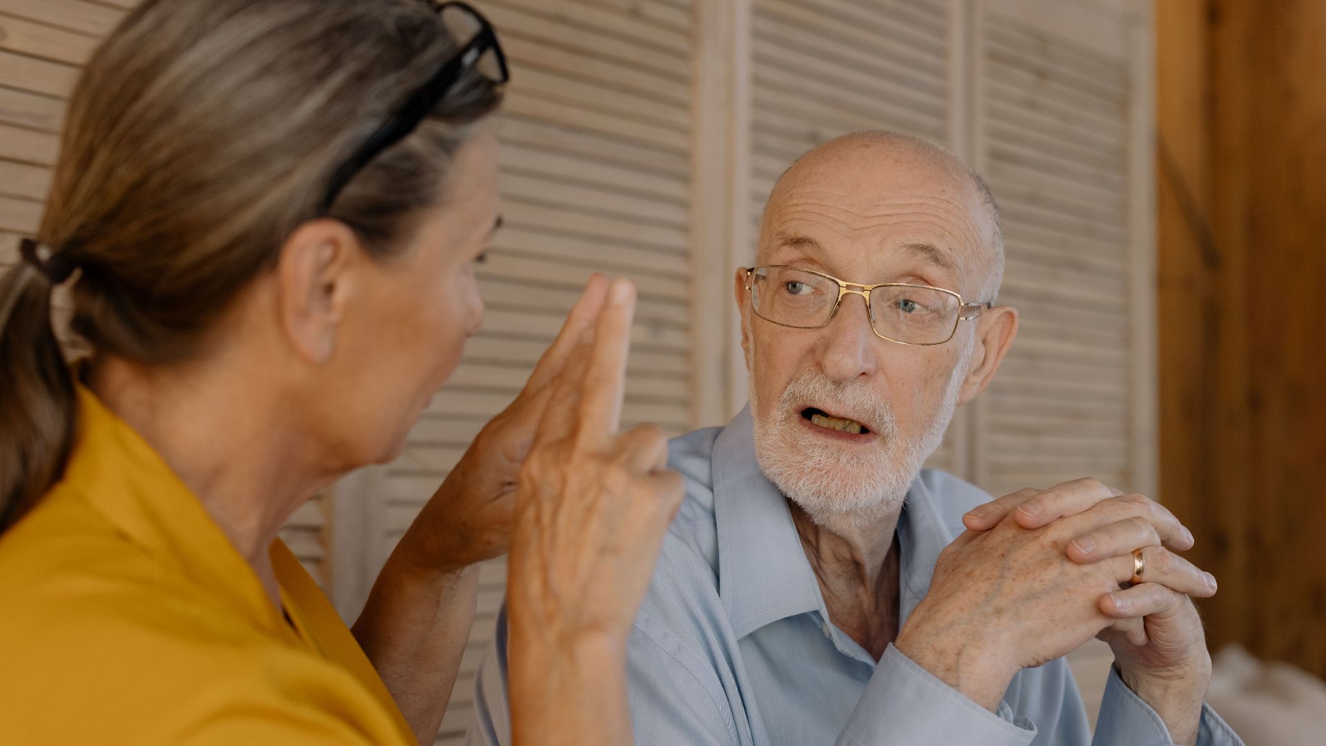 Elderly couple having an engaging conversation indoors, showcasing connection and emotion.