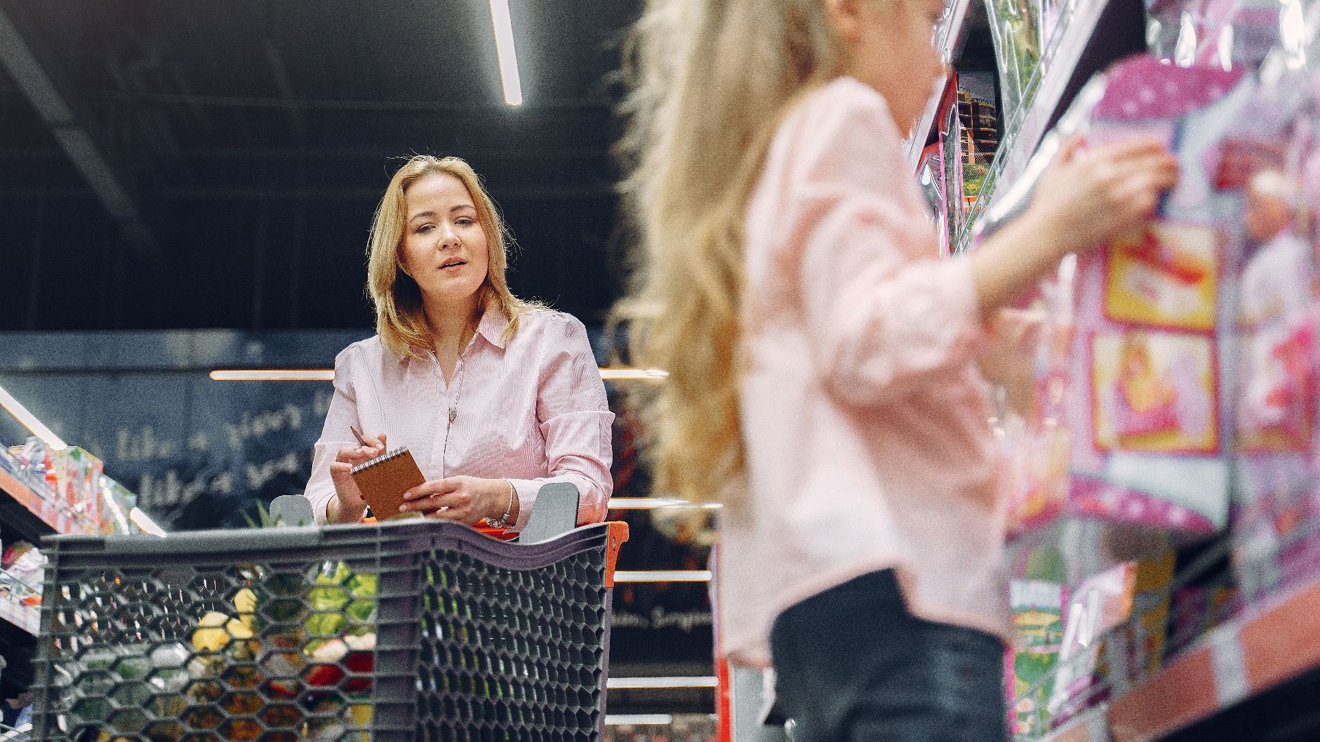 Mother and daughter shopping together in a supermarket, focused on selecting the right products.