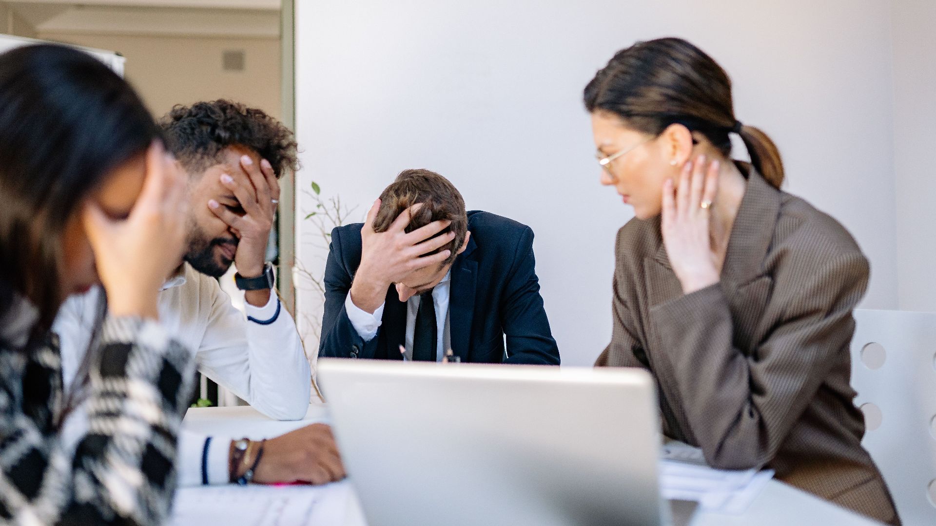A group of stressed business professionals in an office setting, overwhelmed by work.