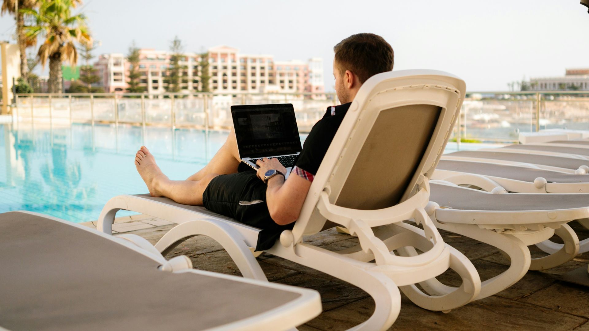 man on sun lounger using laptop