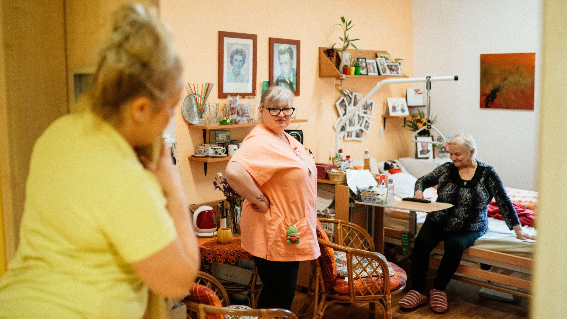 Caregivers interacting with a senior woman in a cozy retirement home in Karviná, Czech Republic.