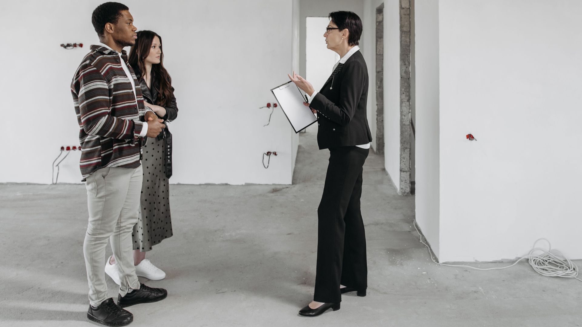 Real estate agent showing a house to a couple in a newly built home interior.