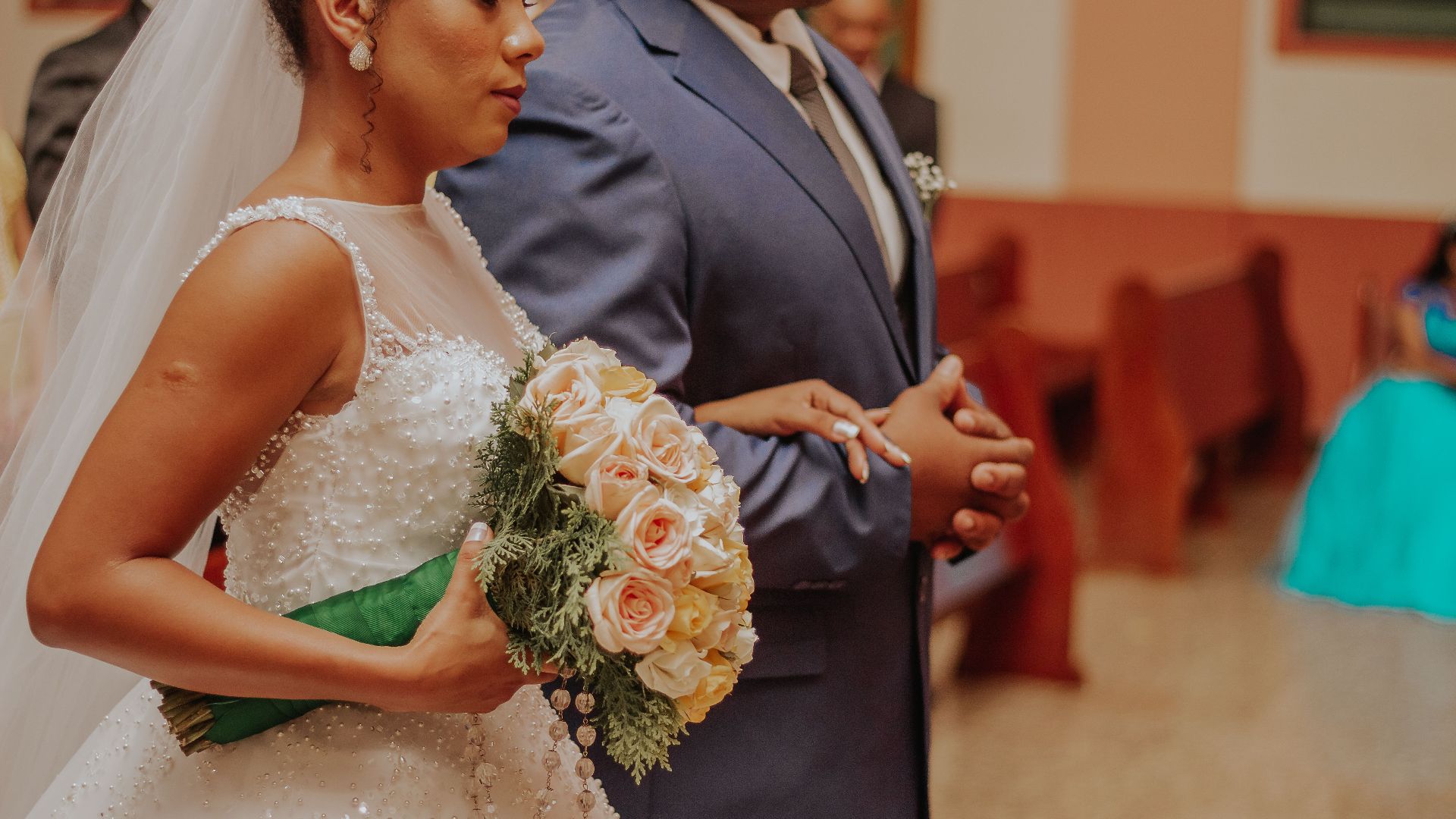 Bride holding bouquet standing next to groom during an elegant wedding ceremony indoors.