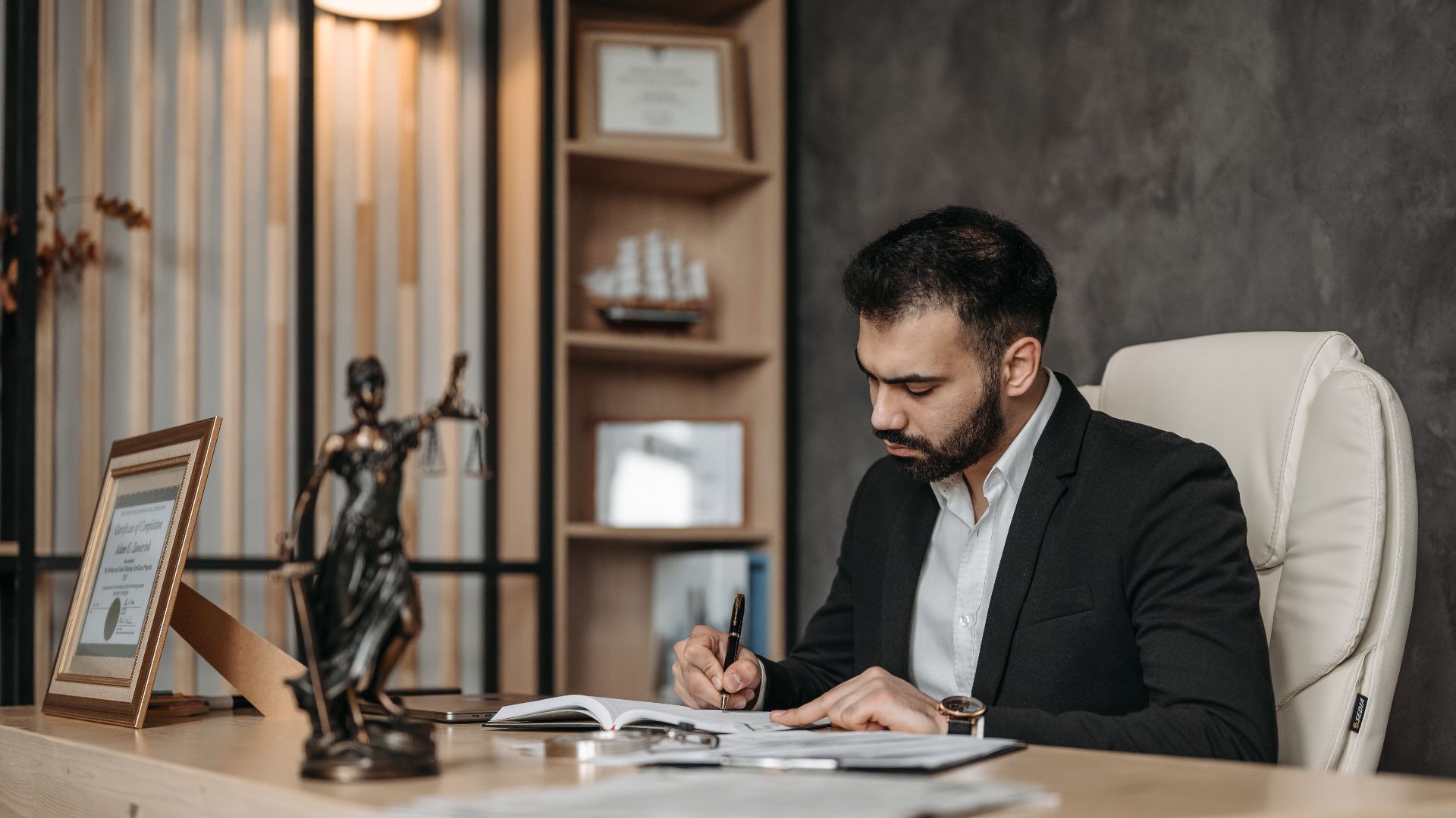 A focused lawyer in an office setting writing and reviewing legal documents, symbolizing expertise and professionalism.