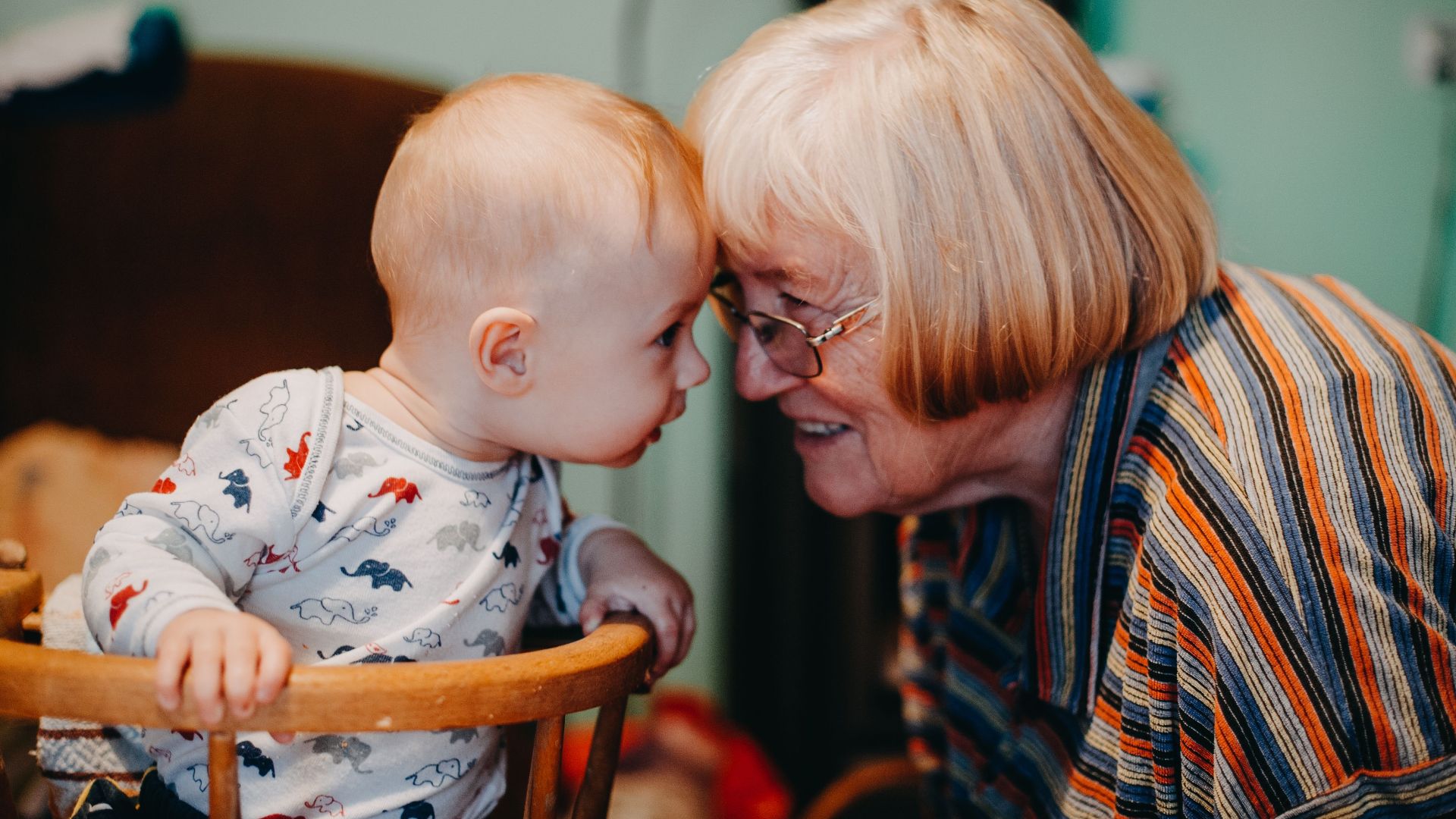 A touching moment shared between a baby and grandmother indoors.