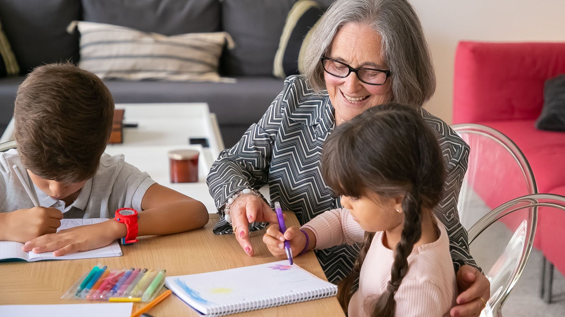 A joyful grandmother assists her grandchildren with their homework indoors.