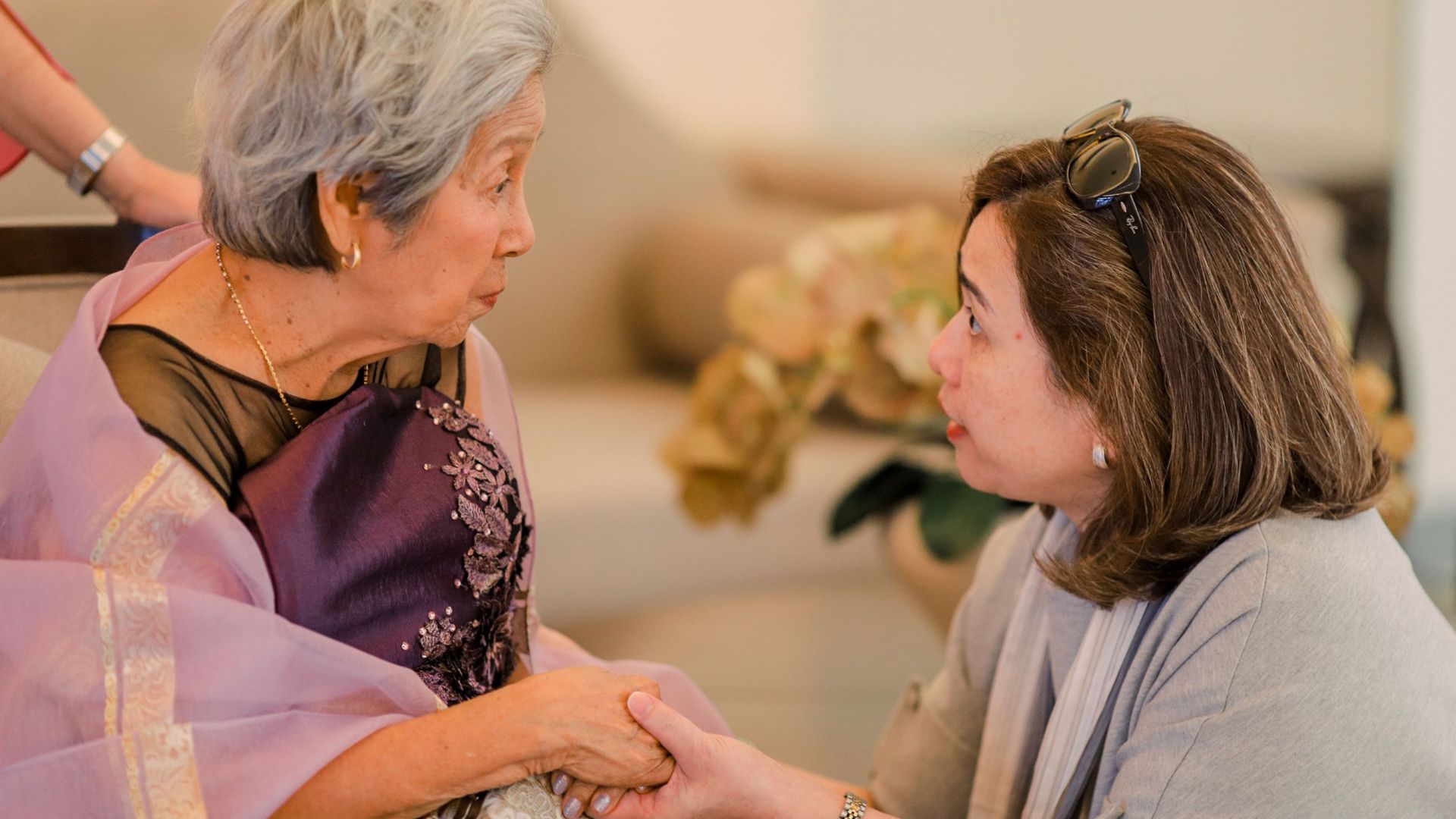 Heartwarming interaction between a senior woman and her adult daughter indoors.