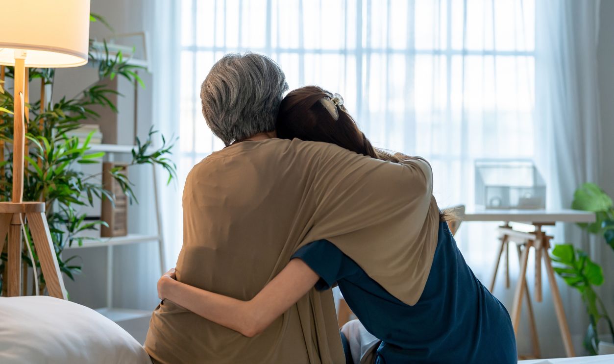 Rear view of elderly mother comfort upset daughter crying for problem. Caring senior mature mom support, consoling and understand empathy to stressed young woman in tears at home. Family relationship.