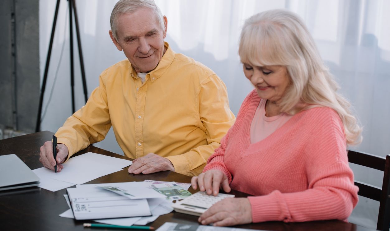 senior coupe sitting at table with calculator and counting money