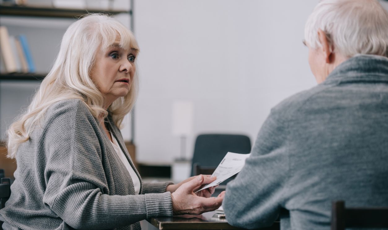 senior couple sitting at table and holding document at home