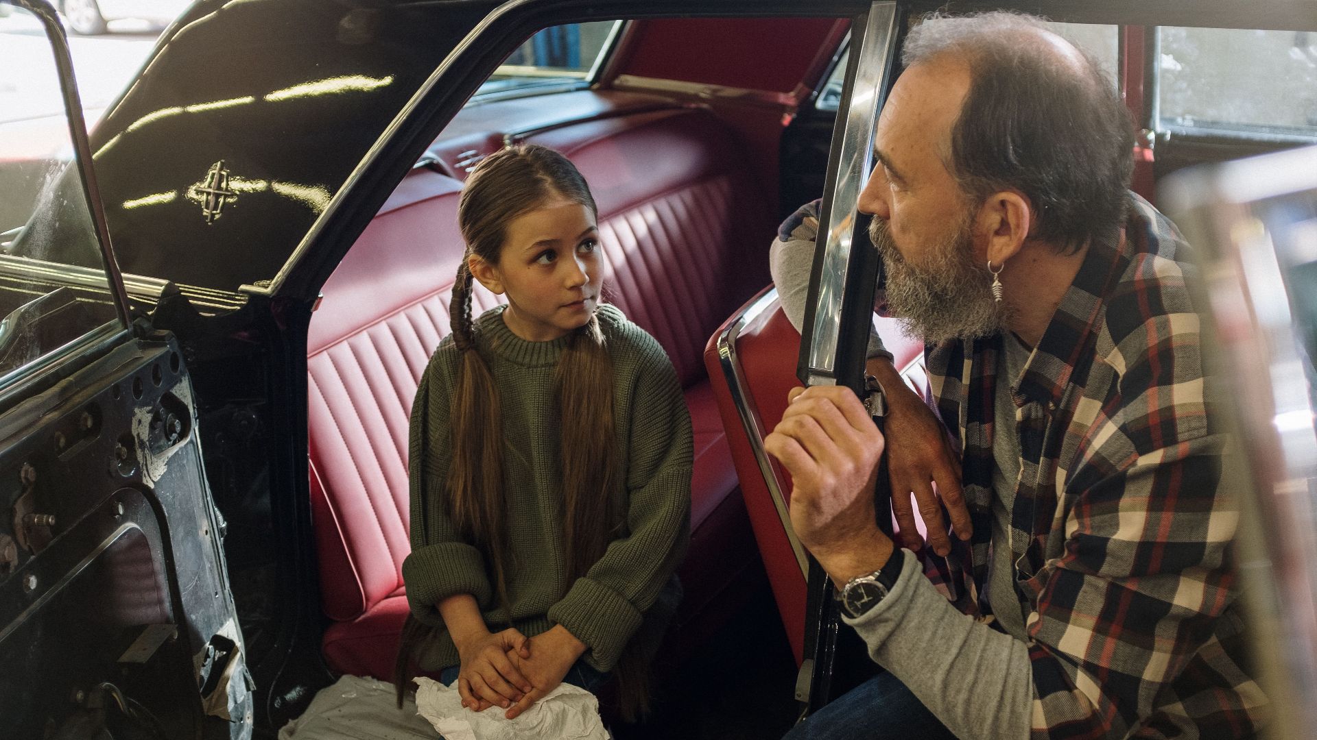 Father and young daughter share a moment inside a vintage car, highlighting family togetherness and nostalgia.