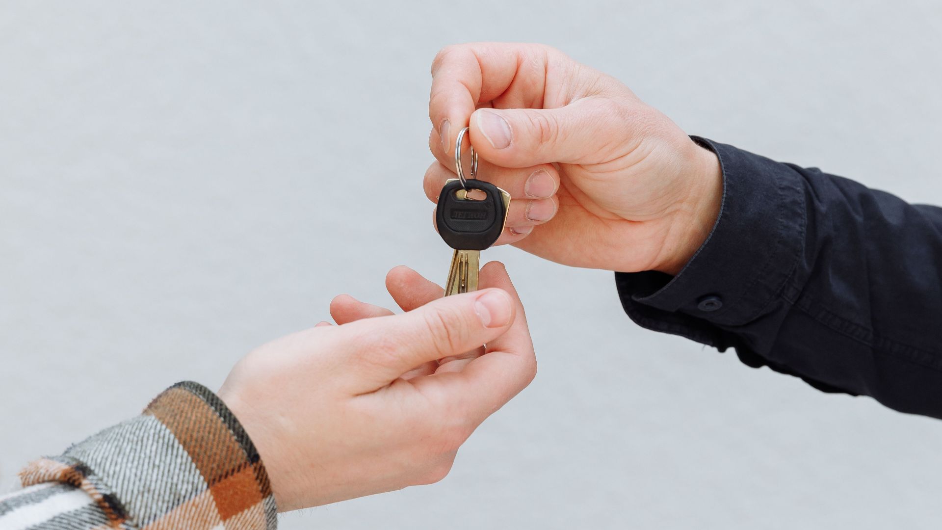 Close-up of hands exchanging car keys, symbolizing a business transaction.