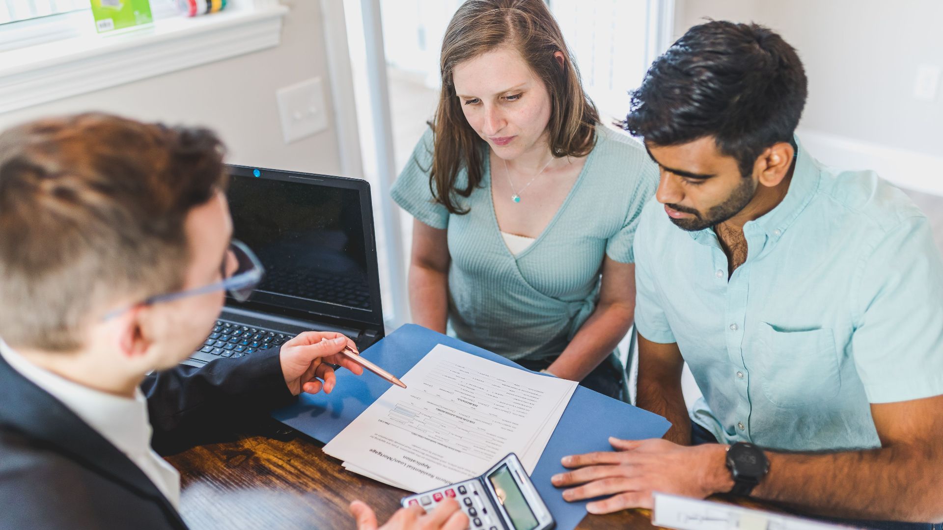 Young couple meeting with real estate agent to discuss property purchase.