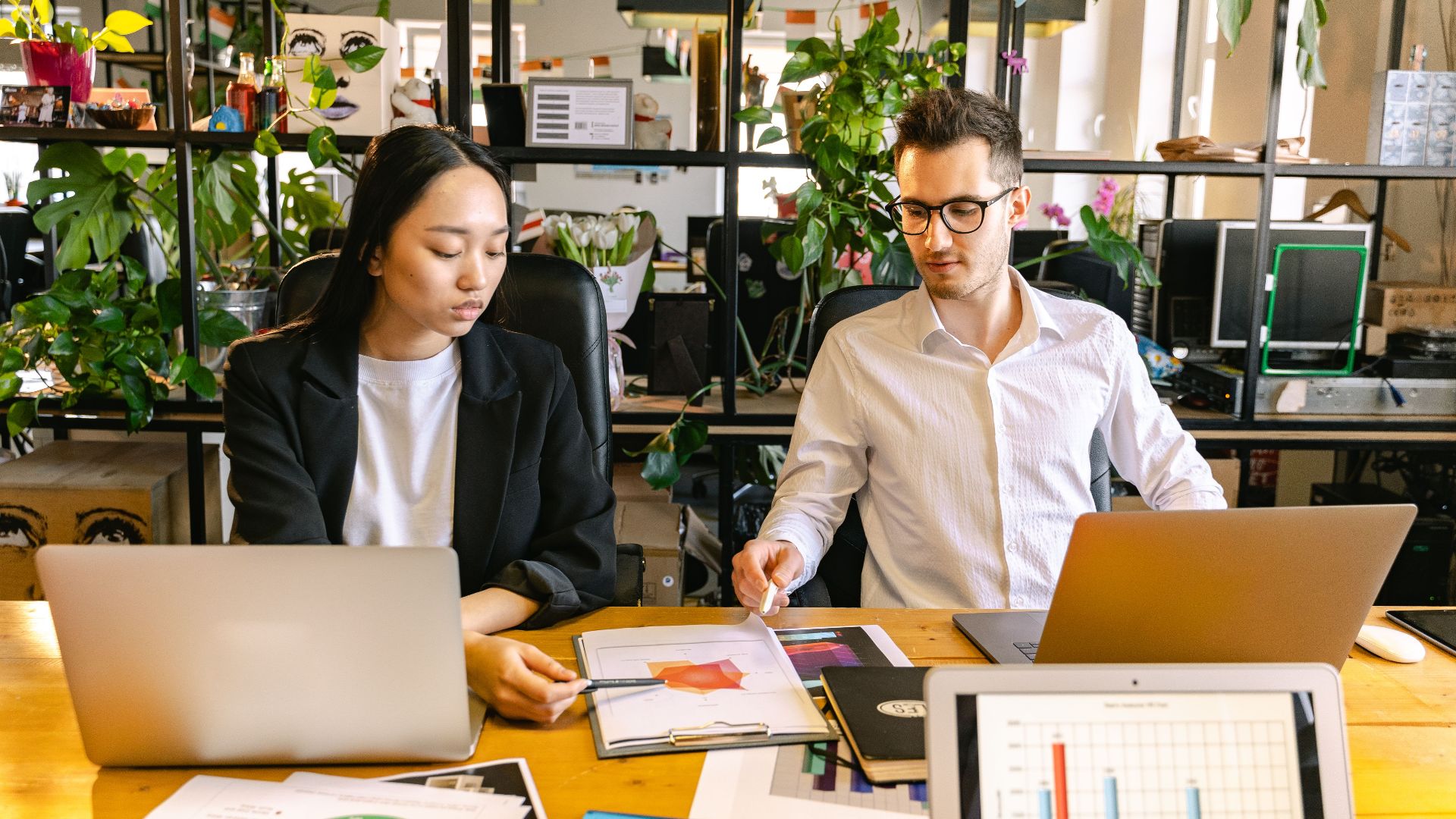 Two colleagues discussing business reports at a modern indoor office space.