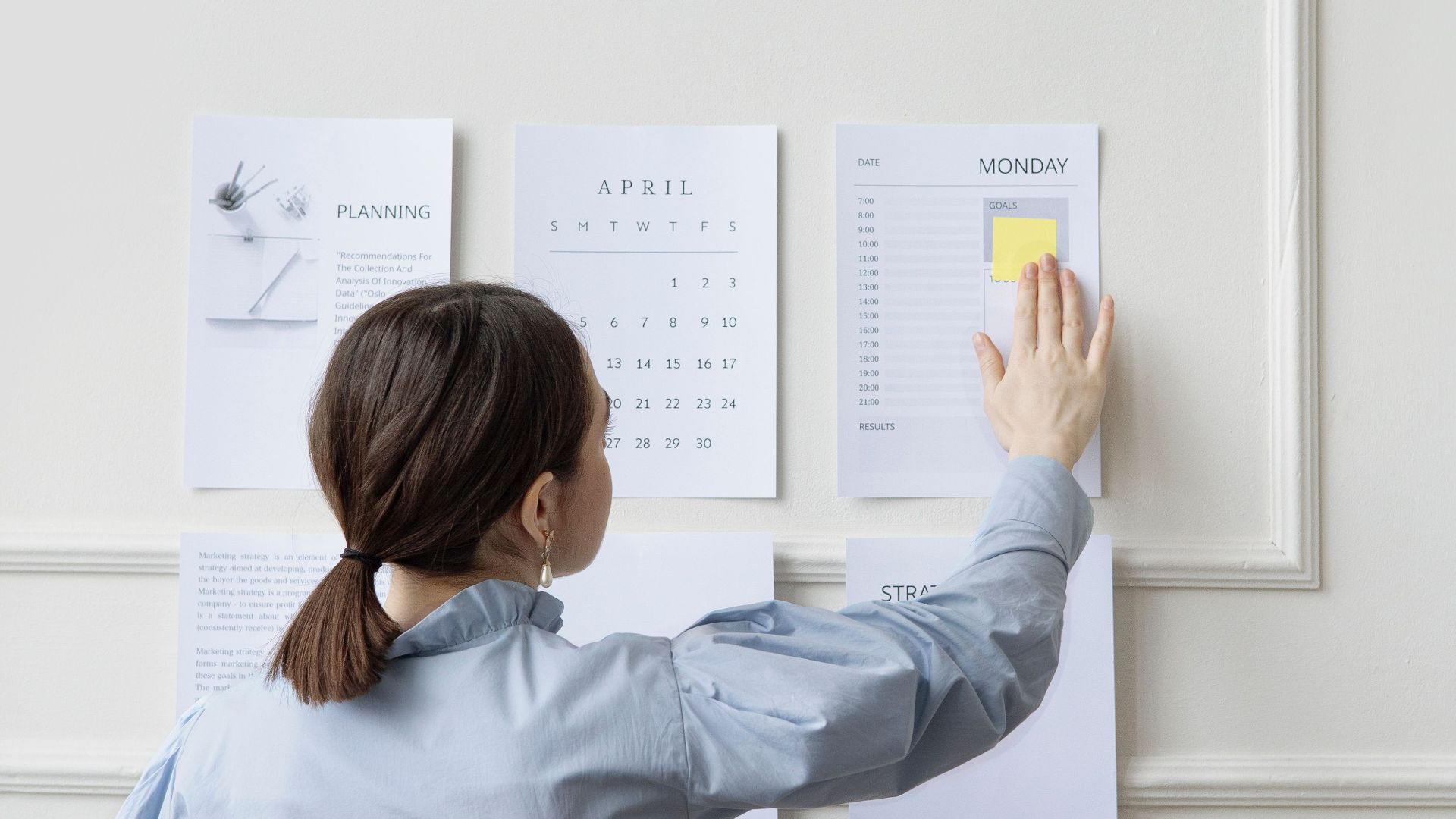Woman organizing wall planner in office showing strategy and planning.