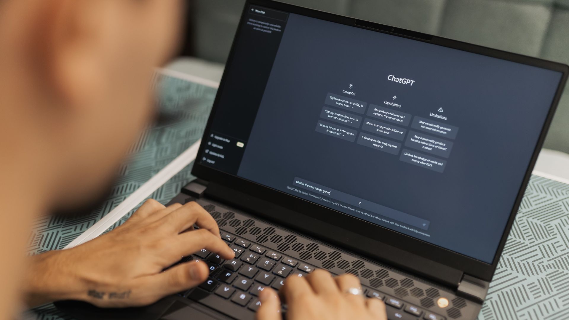 Close-up of a person typing on a laptop displaying the ChatGPT interface, emphasizing modern technology use.