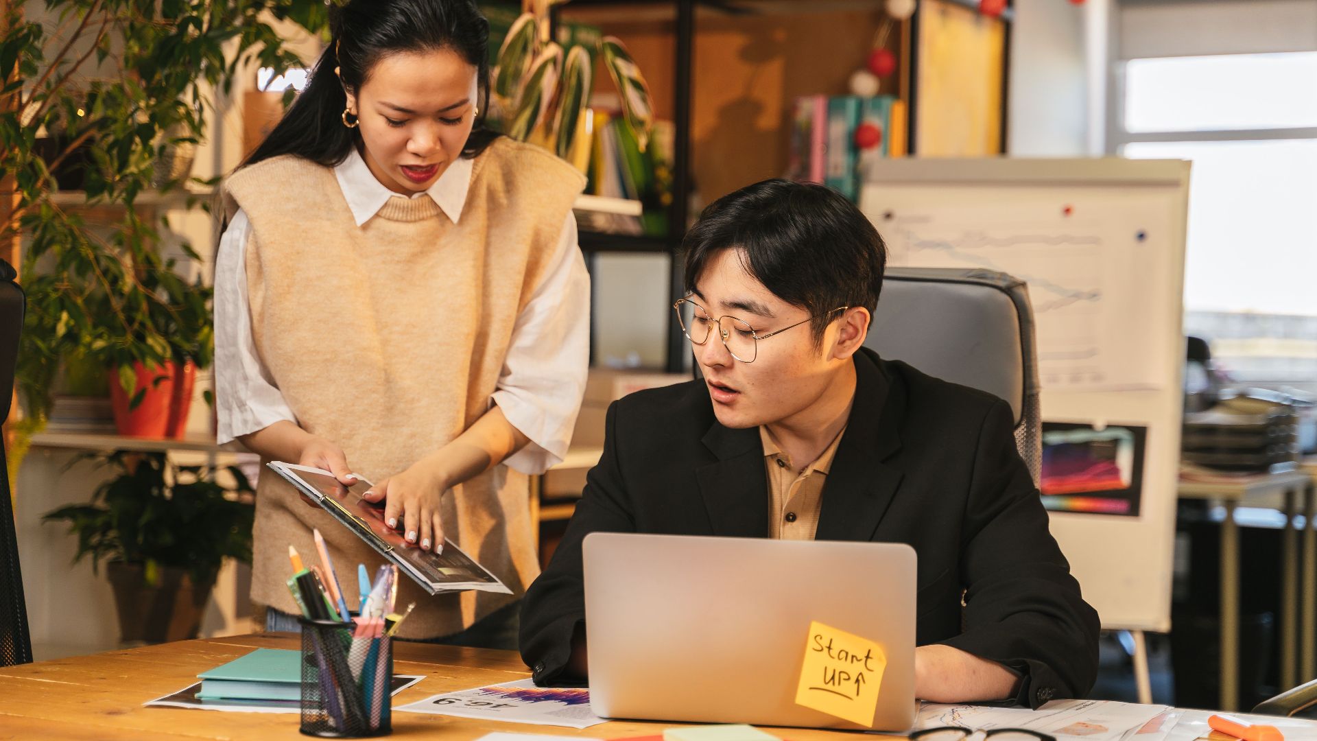 A man and woman engage in a business discussion at a startup office, focusing on teamwork and collaboration.