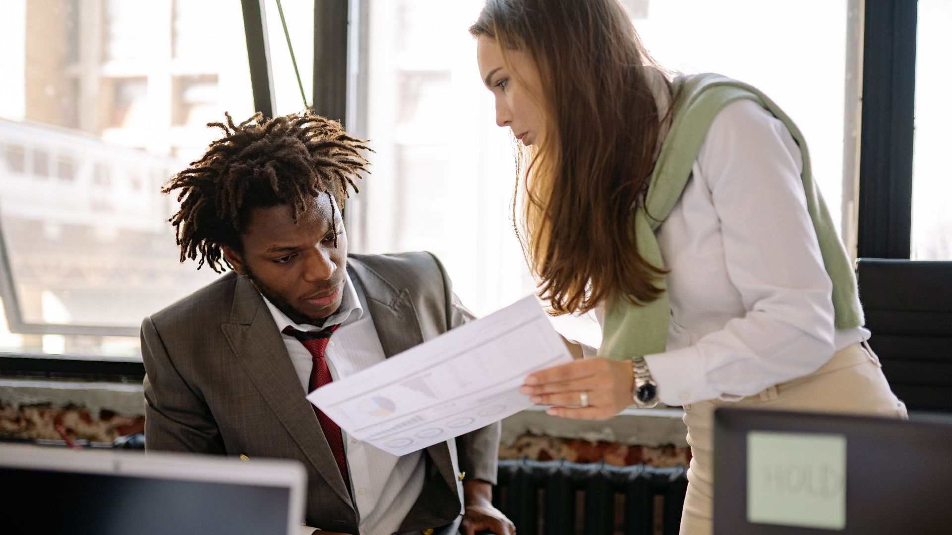 Business professionals in a discussion, reviewing documents in a modern office setting.