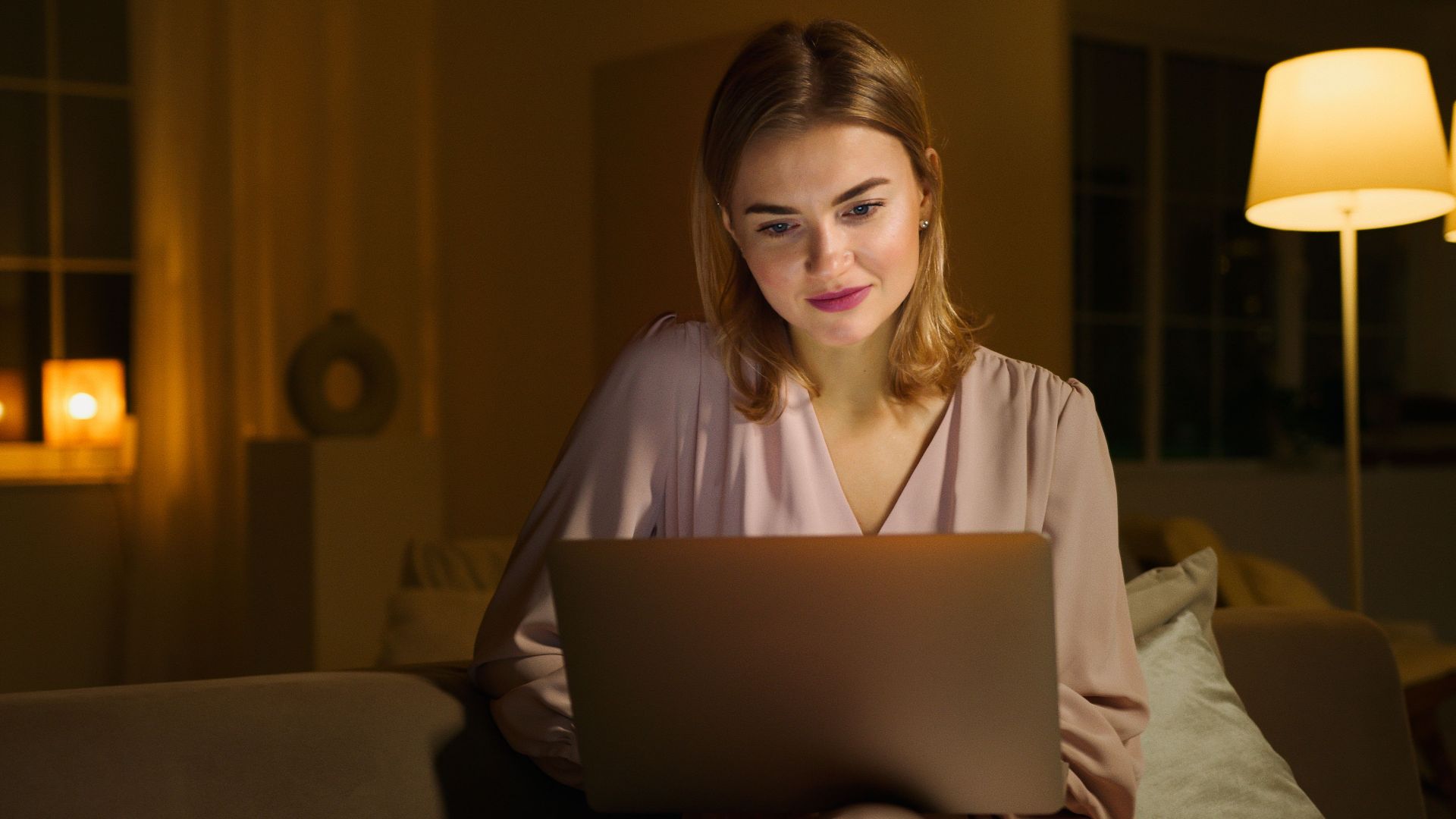 A woman enjoys browsing on her laptop in a cozy and comfortable living room.