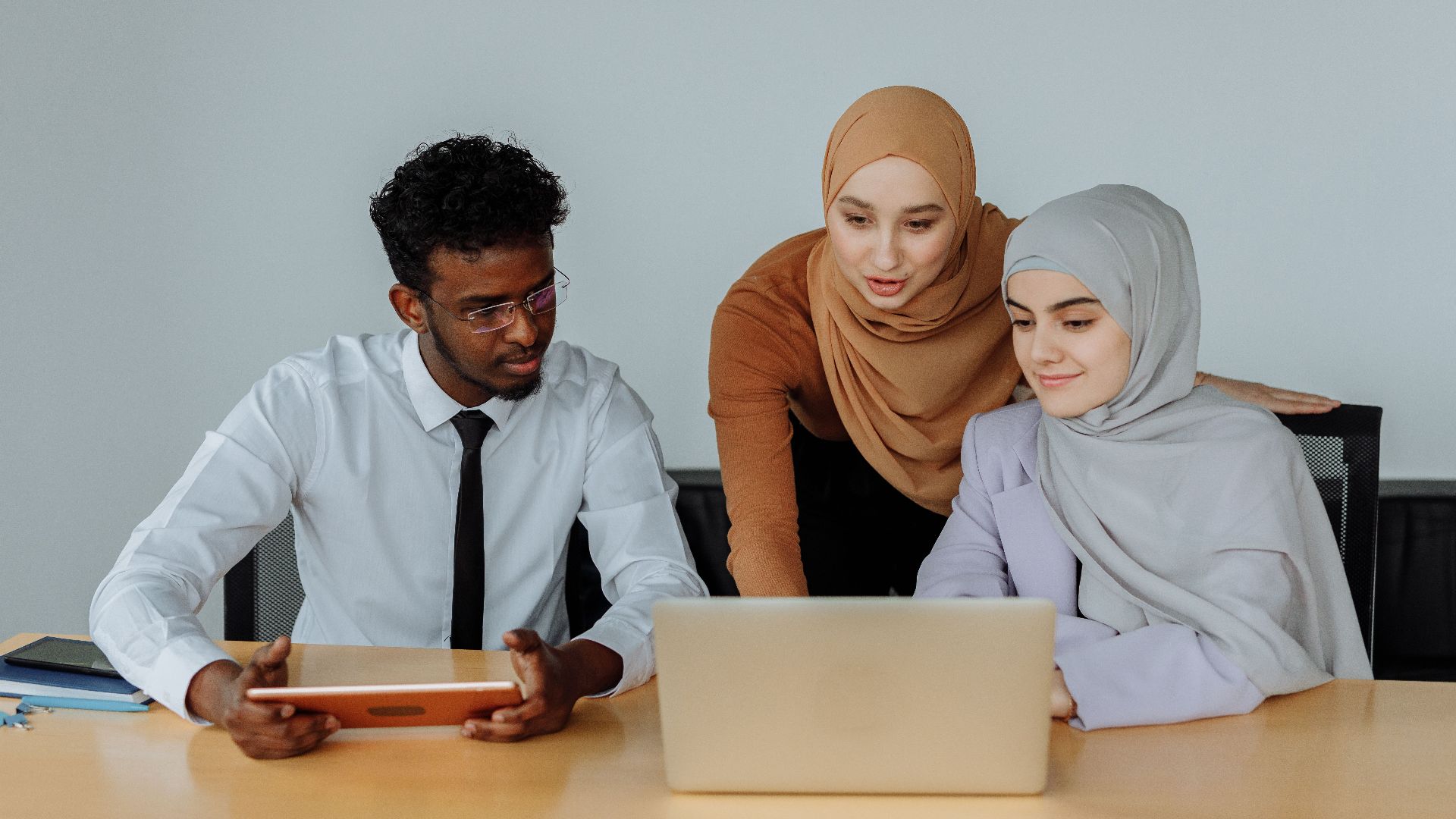 Multicultural team discussing project on laptop in conference room.