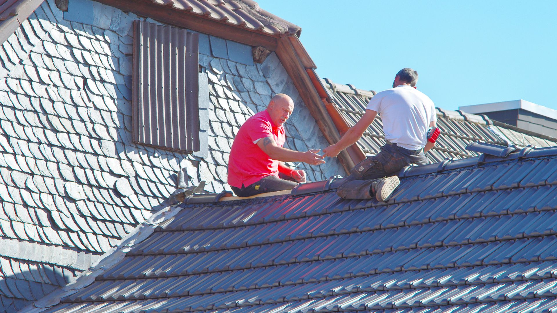 two men working on the roof of a house
