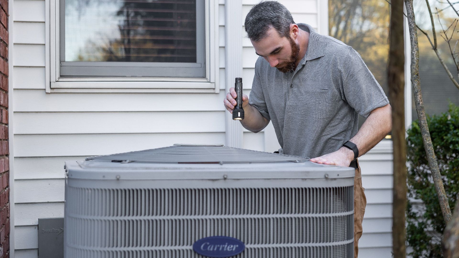 A technician inspects an outdoor HVAC unit for maintenance.