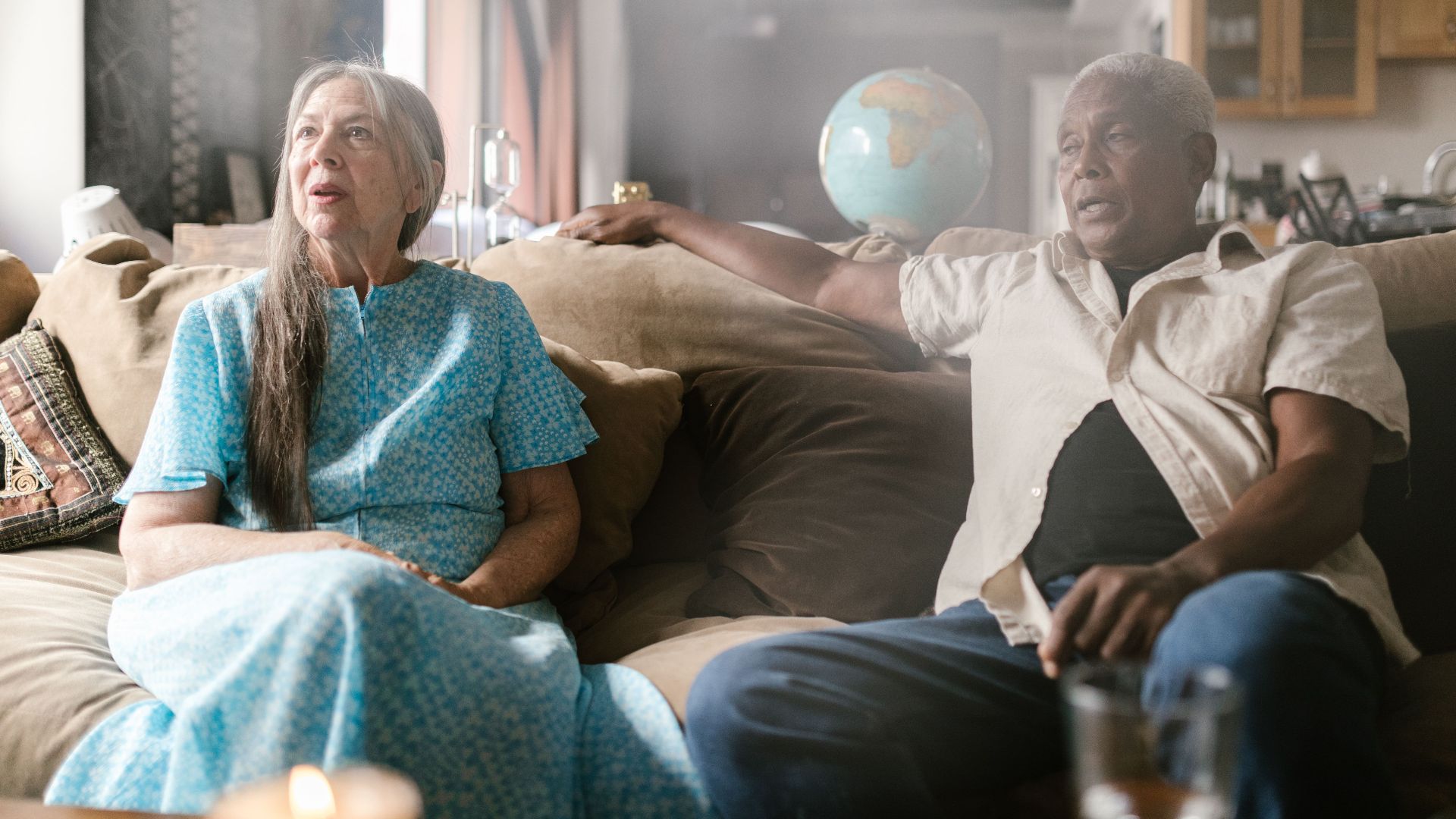 Senior couple sitting on sofa indoors, enjoying a peaceful moment together.