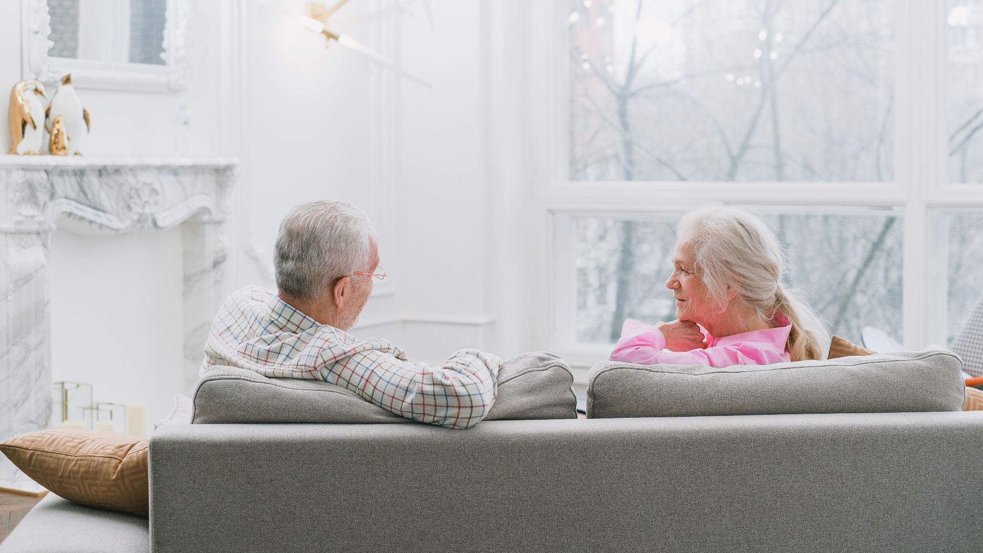 An elderly couple enjoying a quiet moment together on their sofa in a well-lit living room.