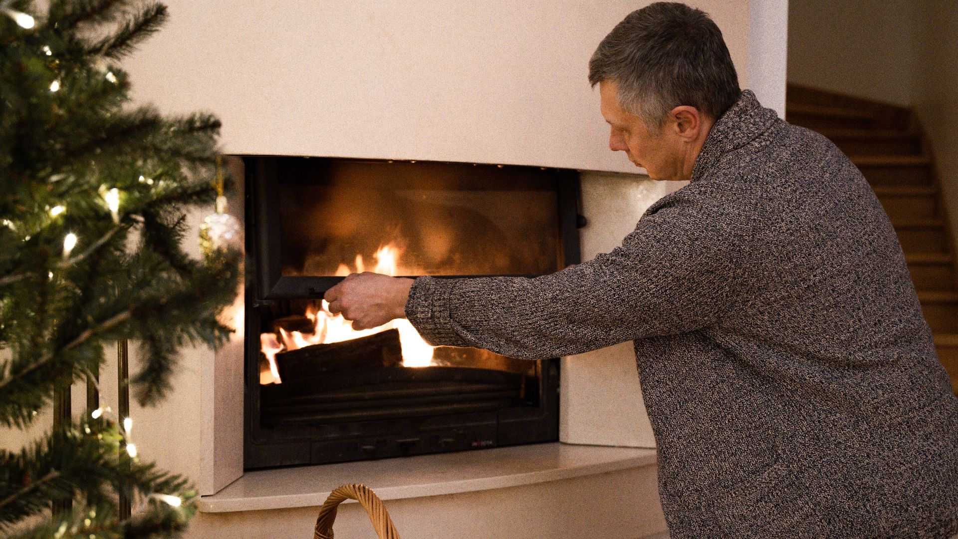 Man tending to a warm fireplace in a cozy home setting during winter.