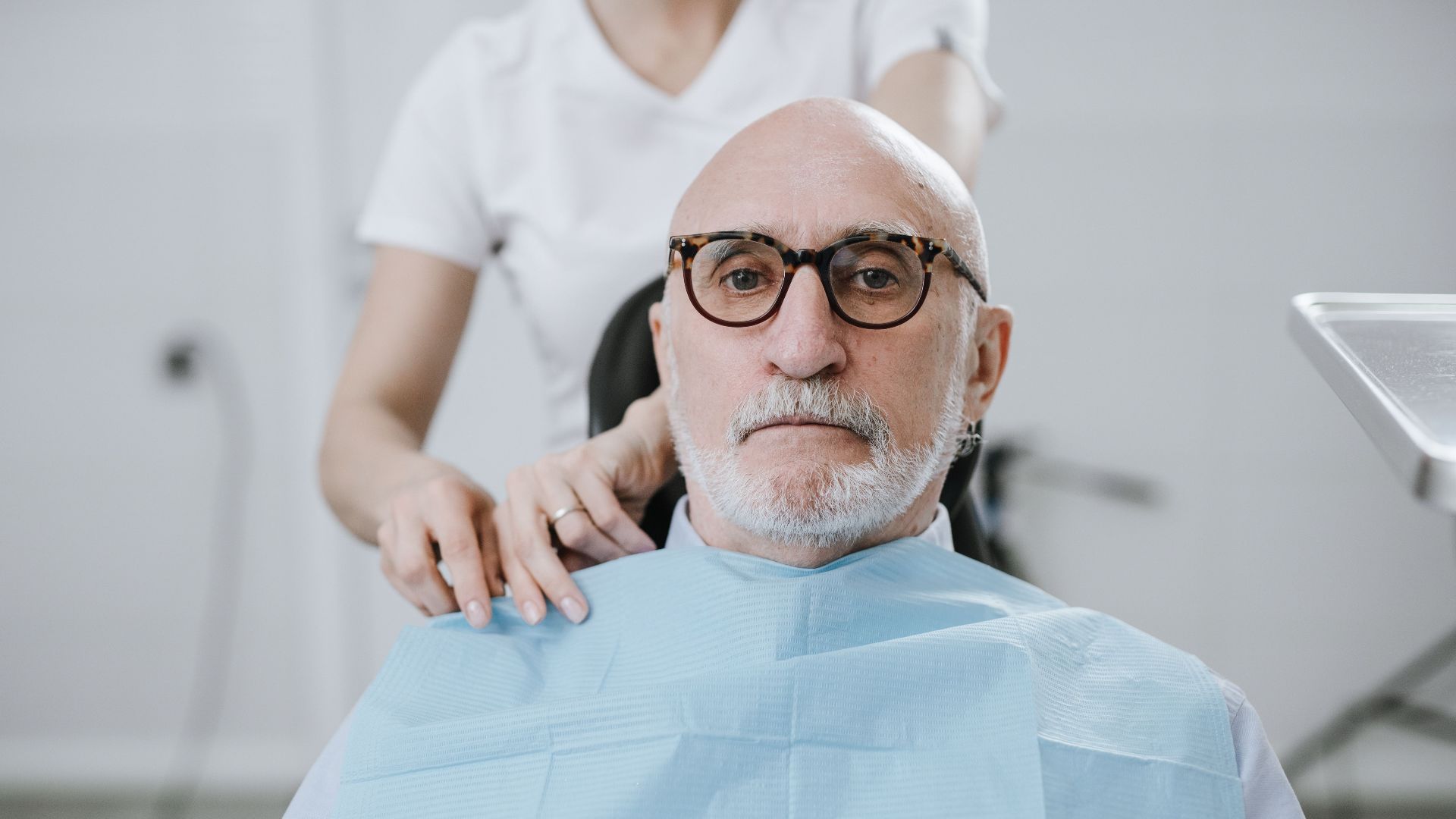 Elderly man in dental chair during appointment, receiving care from dentist.